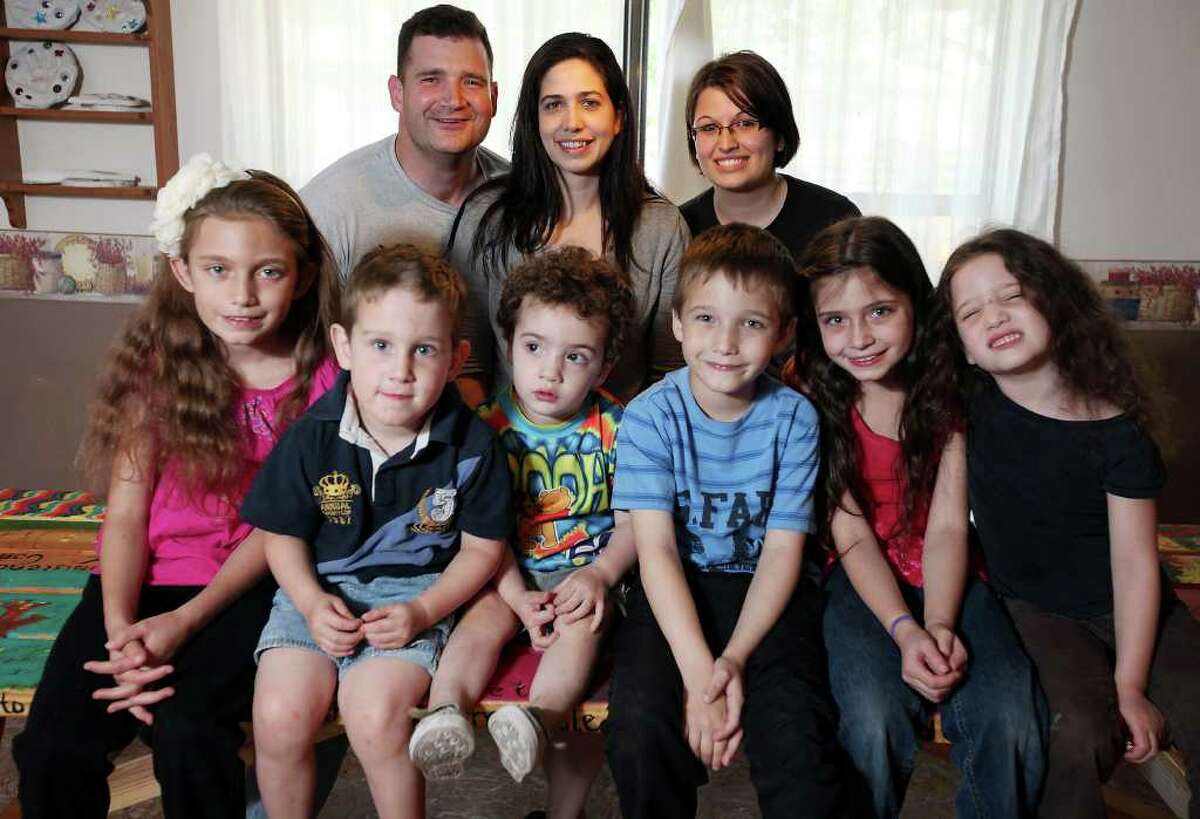 Melissa Anderson (center, back row) poses between her husband, Jared, and sister Kayli, 20, whom the couple adopted. The couple's six children are Elizabeth, 9 (from left); Timothy, 3; John, 2; Samuel, 6; Magdalyne, 8; and Arabella, 5. (PHOTO BY EDWARD A. ORNELAS/eaornelas@express-news.net)