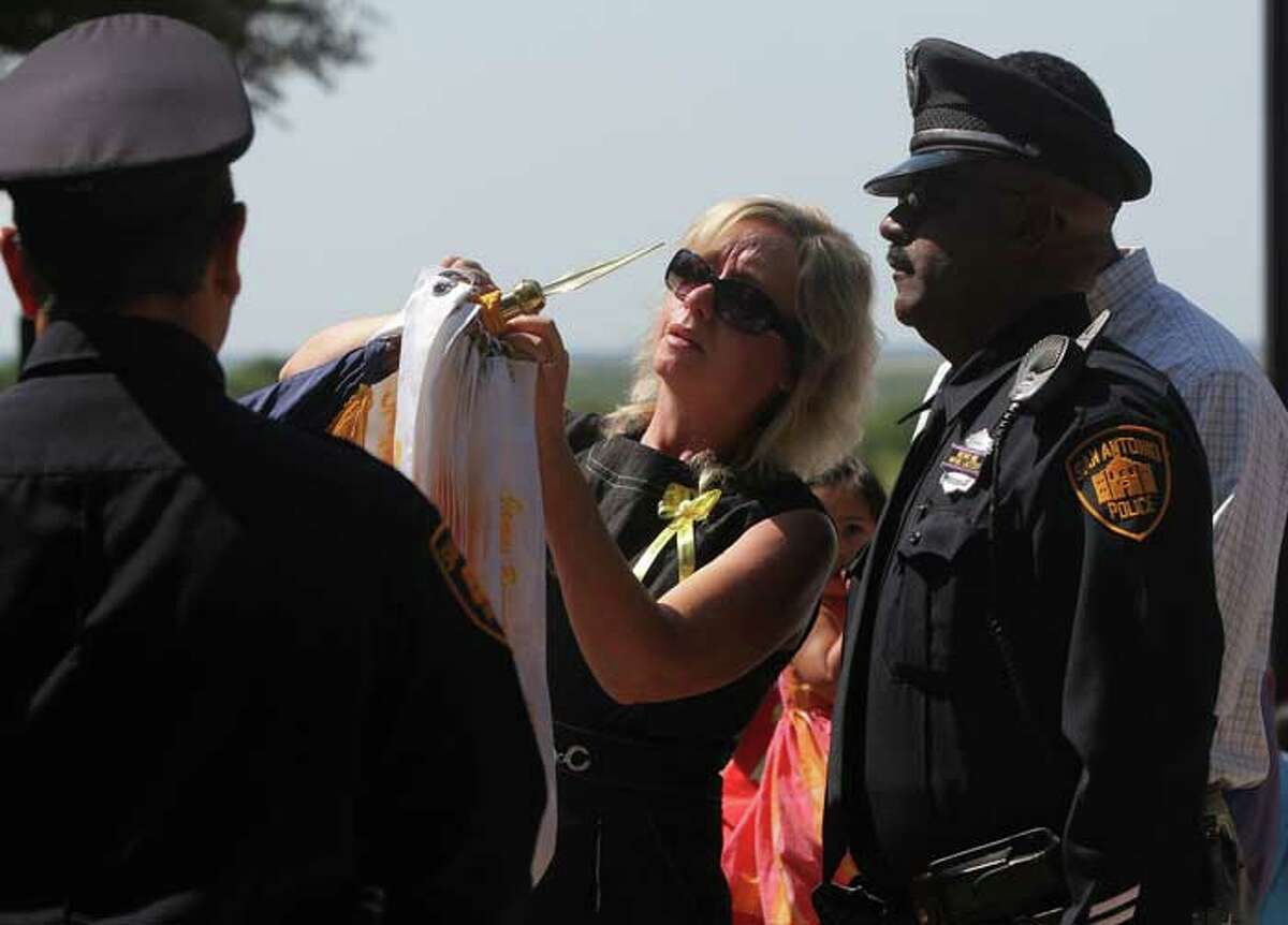 Shawn Brown (center)places a ribbon in tribute to her daughter Stephanie Brown on the San Antonio Police Memorial Flag during a tribute ceremony to fallen San Antonio Police Officers at the police Training Academy Tuesday May 17, 2011. On the right is Stephanie Brown's father Stanley Brown. Stephanie Brown was killed in a car accident while on duty last March. JOHN DAVENPORT/jdavenport@express-news