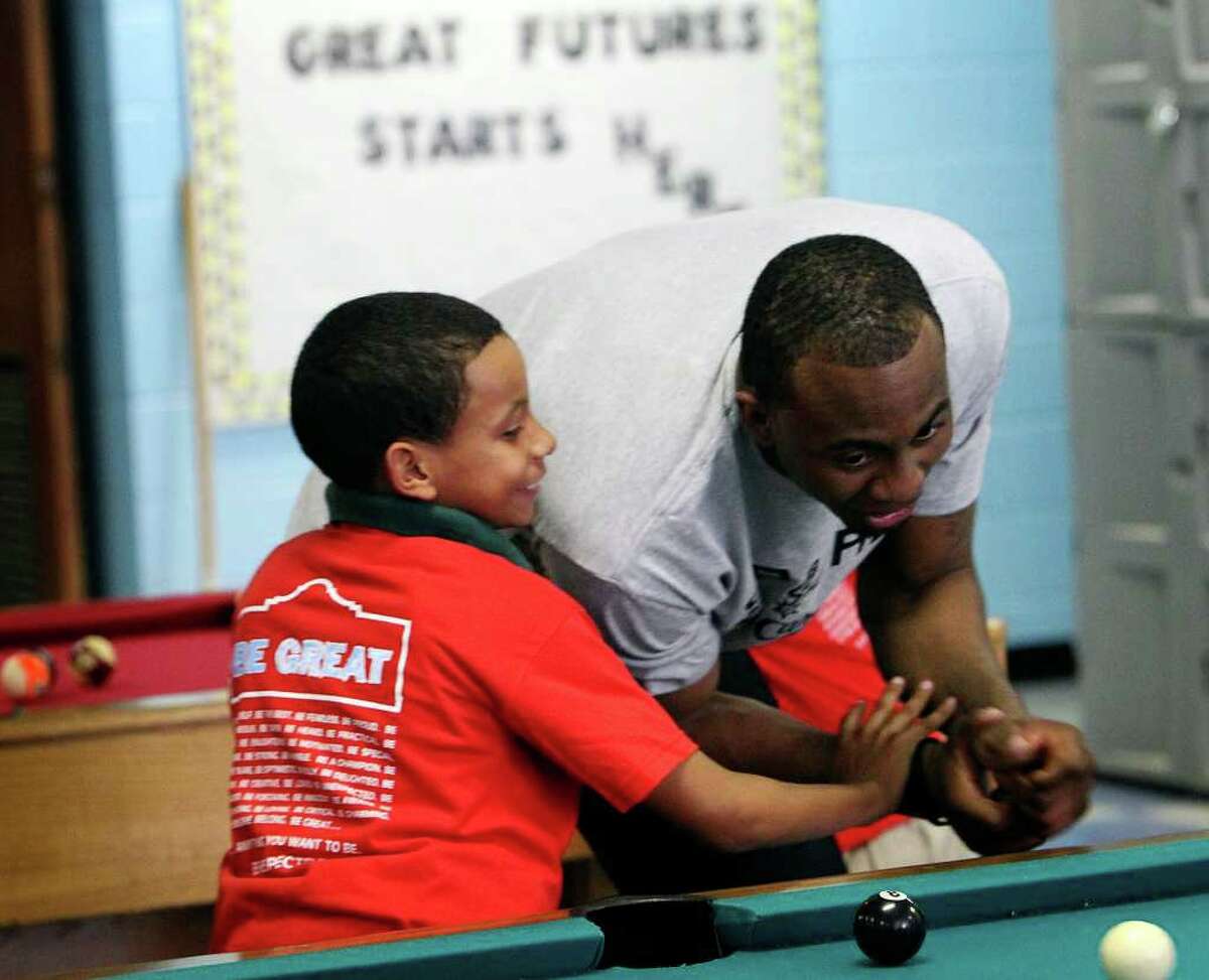 Spurs player James Anderson (right) kids around with Jaylen Sanchez during a game of billiards at the East Side Branch Boys and Girls Club on Tuesday, May 17, 2011. Anderson was joined by teammates Danny Green and Da'Sean Butler. The trio met and played games with the kids during their visit.