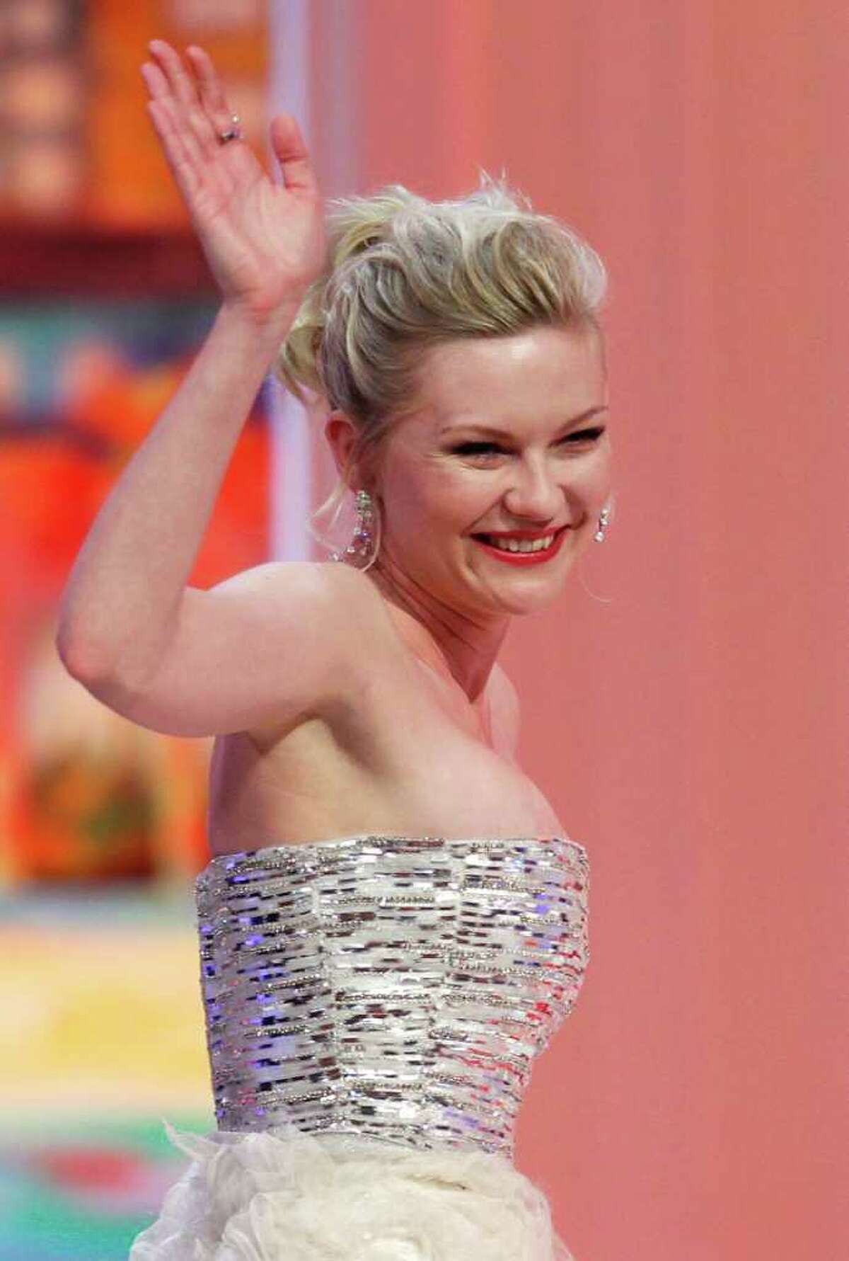 Actress Kirsten Dunst gestures to the crowd as she goes to accept the Best Actress award for the film Melancholia during the awards ceremony at the 64th international film festival, in Cannes, southern France, Sunday, May 22, 2011. (AP Photo/Francois Mori)