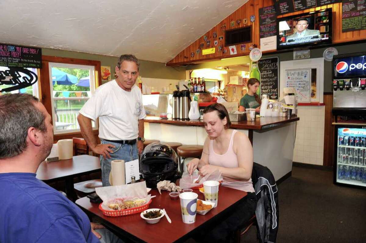 Ron "R.W." Wishna, of Ridgefield, center, owner of RW's BBQ in Brookfield, talks with dinner customers Anthony Mills, left, and Kate Johnston. Photo taken Friday, May 27, 2011.