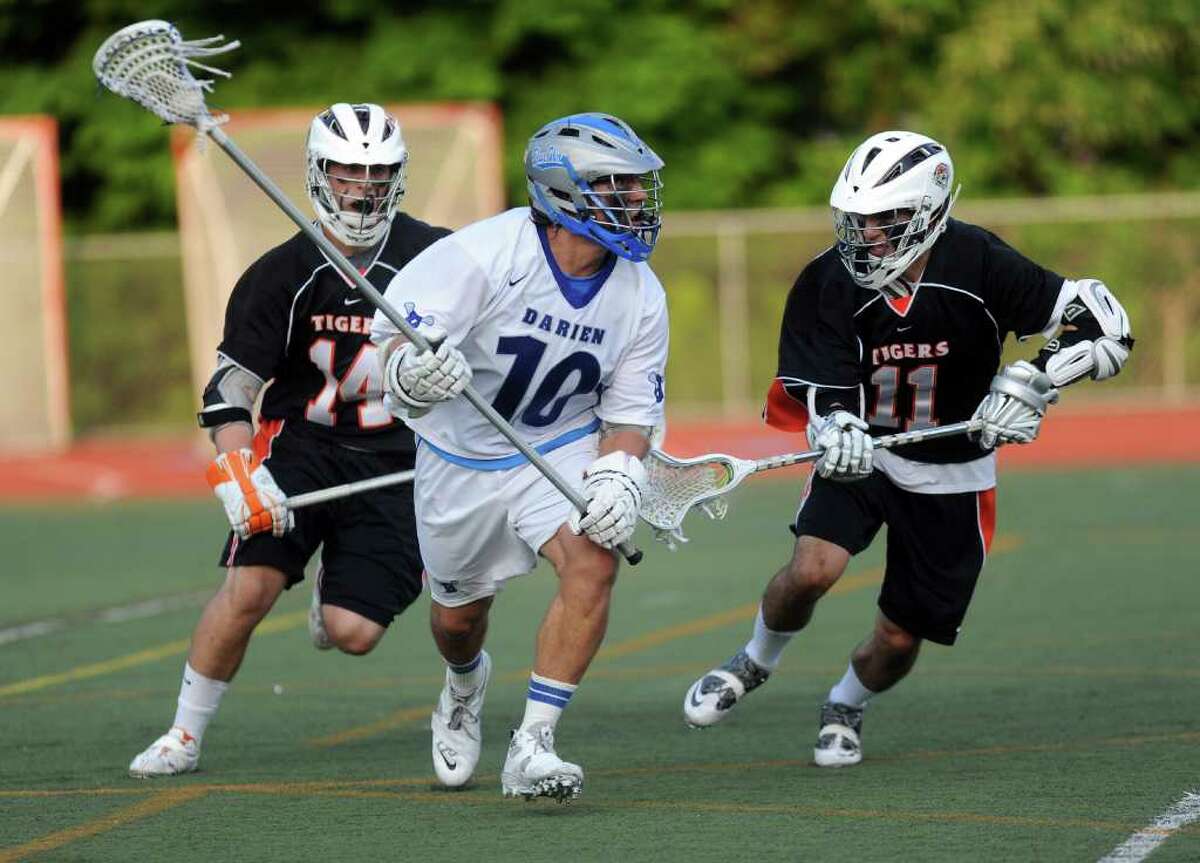 Darien's Tony Britton carries the ball as he is defended by Ridgefield's Matt Hrvatin, right, and Eric Scala, left, during Friday's FCIAC final game at Brien McMahon High School on May 28, 2011.