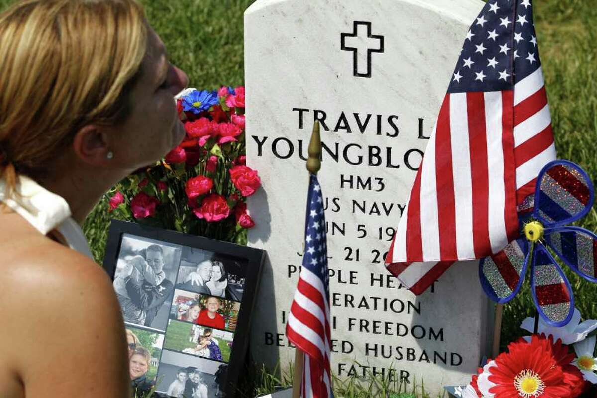Laura Youngblood prays over the grave of her husband Travis L. Youngblood at section 60 in Arlington National Cemetery, Monday.