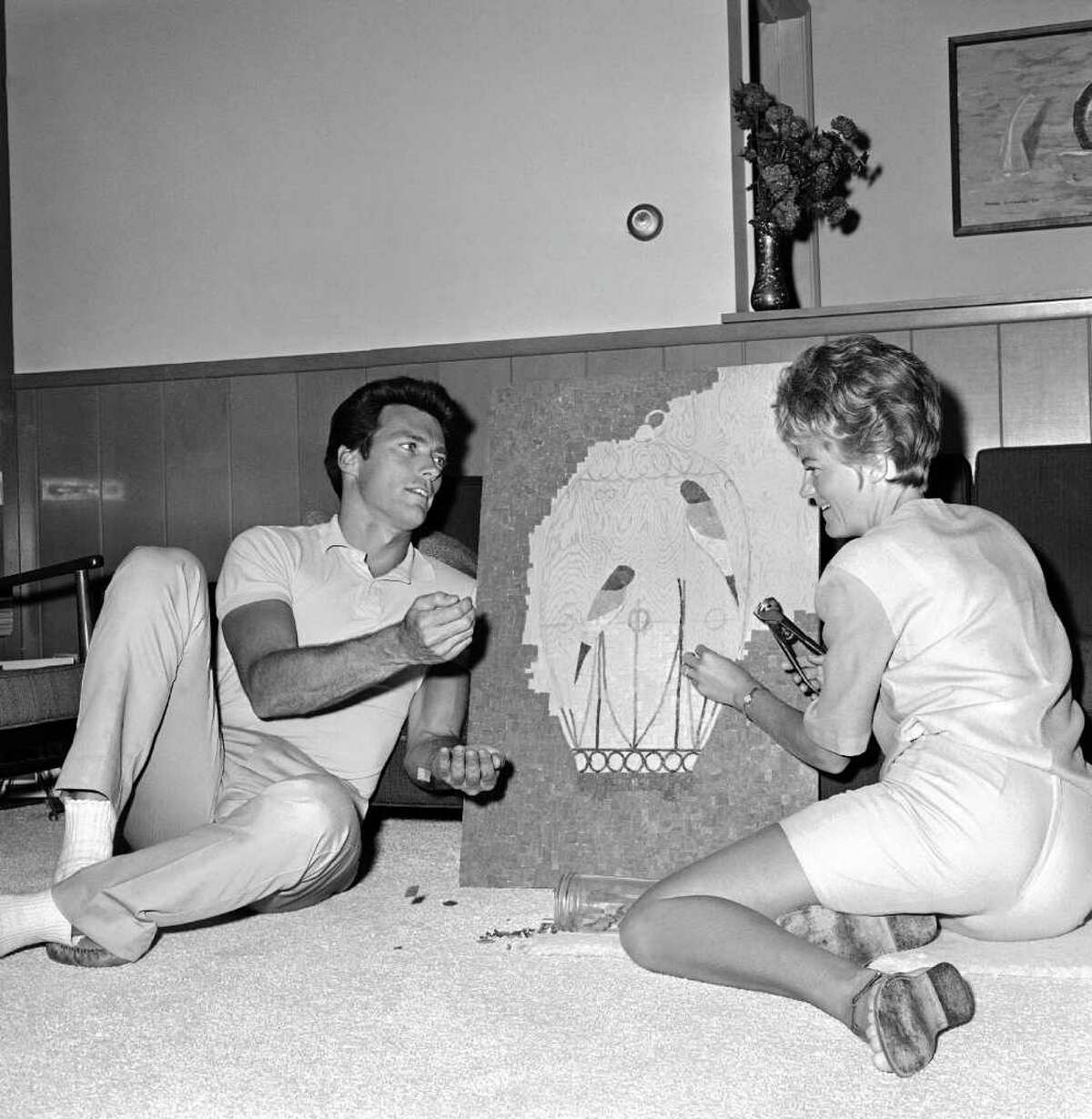 A helpful male, actor Clint Eastwood keeps the bits of tile handy for a mosaic his wife Margaret is making, in their home at Hollywood Hills, Calif, Oct. 25, 1962. Clint finds the floor a nice spot to rest as he helps.