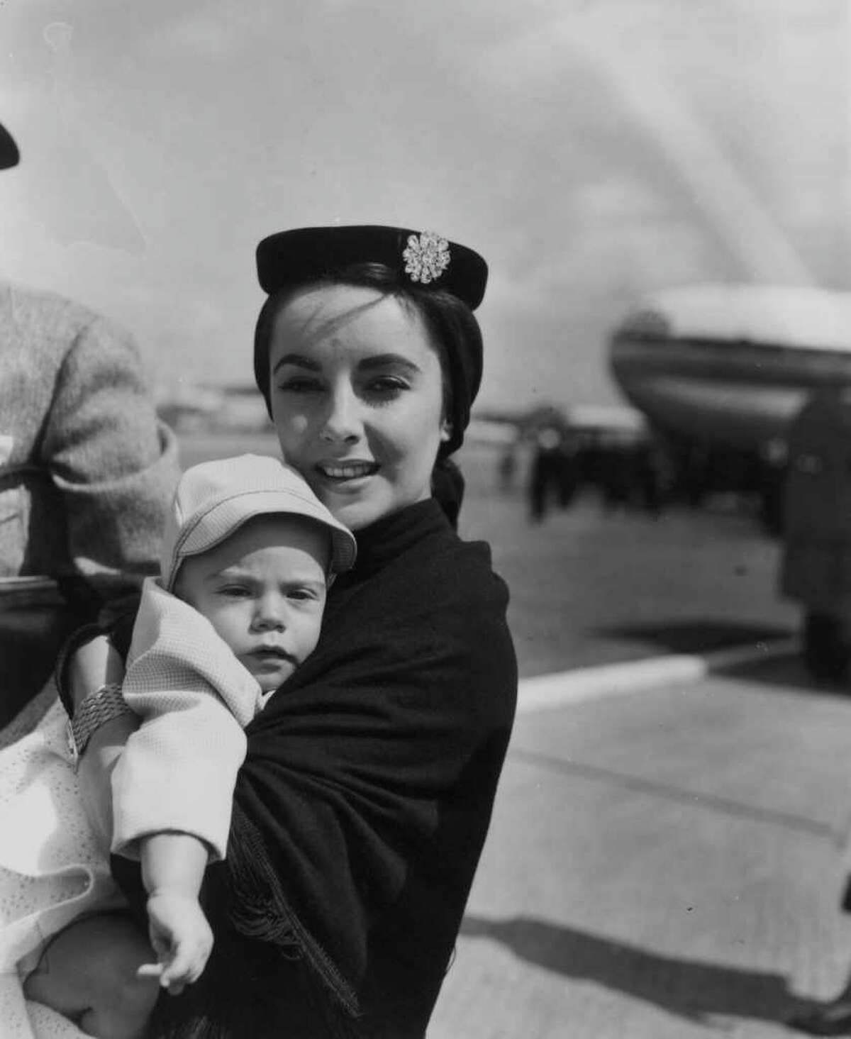 Elizabeth Taylor carries son Michael Howard, aged 7 months, at London Airport, circa 1955.
