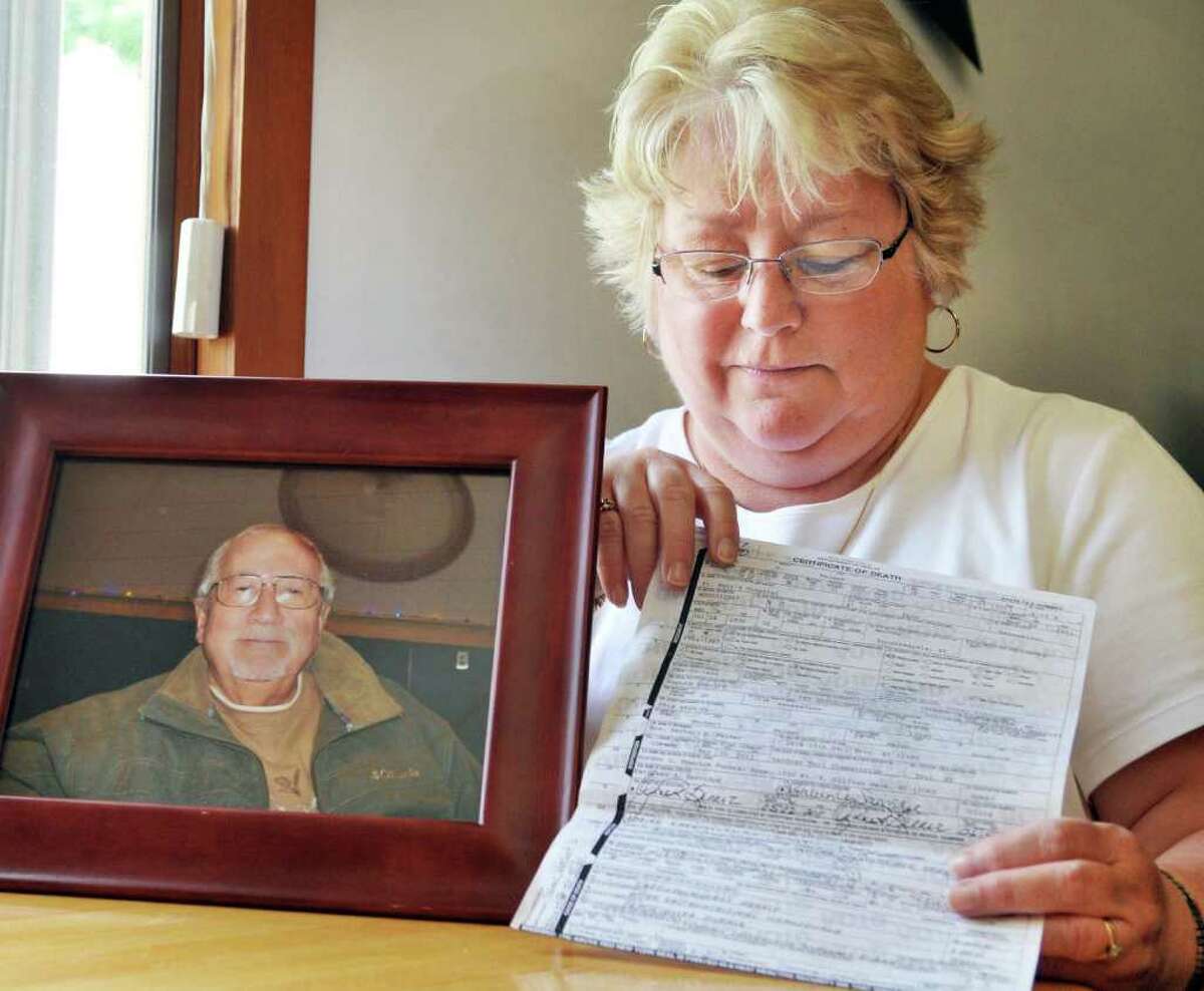 Sue Palmer with a portrait of her late husband Herbert and a copy of his death certificate in the kitchen of her Troy home Friday morning May 27, 2011. (John Carl D'Annibale / Times Union)