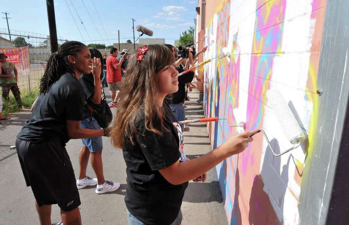 Kayla Gutierrez of the Guadalupe Cultural Arts Center's Team Up Challenge paints over graffiti at the back of the center with Silver Stars player Roneeka Hodges (left) on Wednesday, June 1, 2011. A mural called "Voice of the Voiceless" will be painted on the wall later this summer.