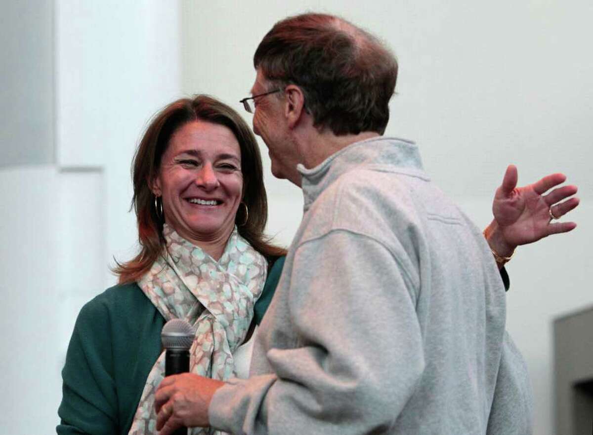 Melinda Gates, left, throws her arm around husband Bill Gates as he introduces her to speak at the opening reception of the Bill & Melinda Gates Foundation Thursday, June 2, 2011, in Seattle. The foundation formally opened the new headquarters Thursday evening, moving from scattered nondescript office buildings around Seattle to an architectural showcase in the center of its hometown.