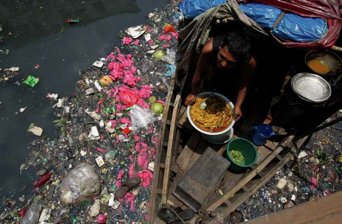 A boatman prepares food in his boat on the polluted river Buriganga in Dhaka, Bangladesh, Sunday, June 5, 2011. World Environment Day is celebrated June 5 every year by the United Nations to stimulate worldwide awareness of environmental issues and encourages political action.