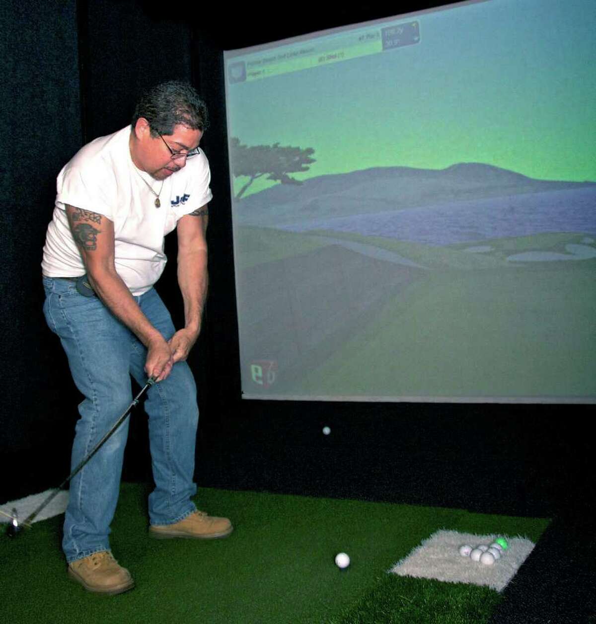 SPECTRUM/Joe Valedon from J & R Appliance Repair, who had never hit a golf ball in his life, takes his shot during the Greater New Milford Chamber of Commerce's 80th anniversary party at a simulated version of the famous 7th hole at Pebble Beach Golf Links in California on the "Golf Simulator" at Phys-Ed Health and Performance in New Milford. The golf simulator is among the attractions at the Still River business. May 20, 2011