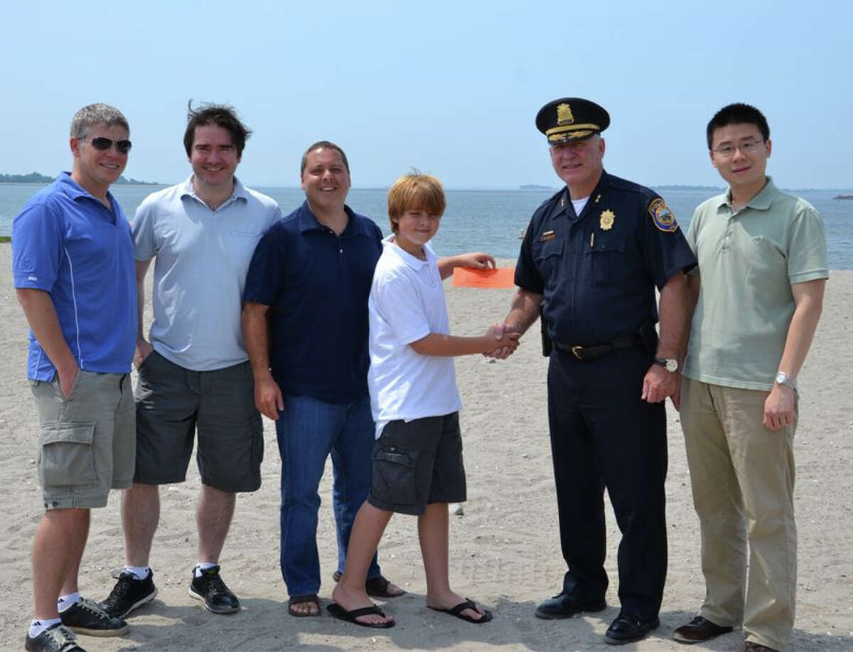 Police Chief Al Fiore presents the first ticket to the Independence Day Fireworks Celebration to Paul Friezo at Compo Beach. Also pictured, from left, are: Mark McKeown, Tom Kennedy, David Friezo and Bing Cui.