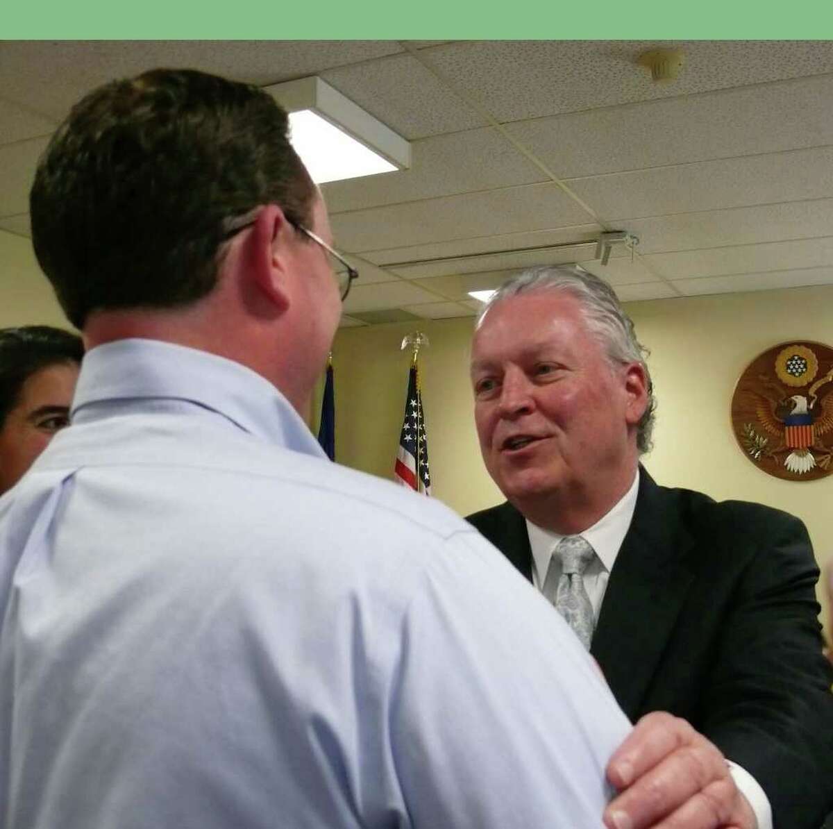 Jamie Millington Republican majority leader of the Representative Town Meeting shakes interim First Selectman Michael Tetreau's hand after a formal ceremony Friday morning.