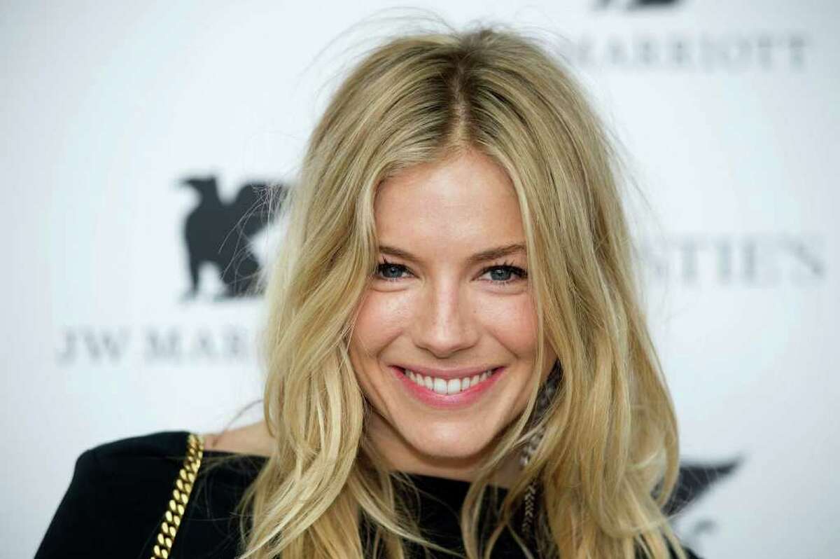 British actress Sienna Miller poses for photographers as she arrives to host a private viewing reception for the forthcoming sale of 'The Beatles Illuminated: The Discovered Works of Mike Mitchell' in central London.