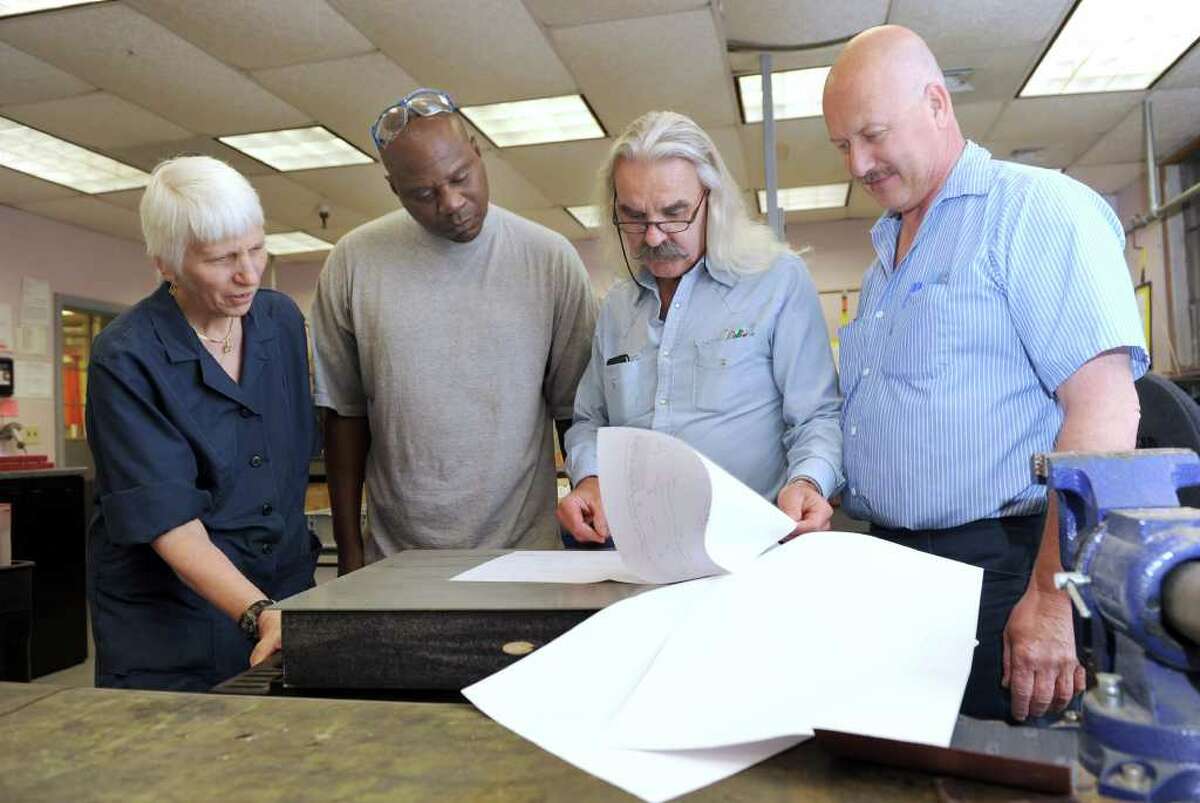 Employees of Gar Electroforming in Danbury,are from left, Diana Peck and Jeffrey Perkins, electroforming technicians, Guy Rosato, quality assurance manager and Russell Richter, vice president and general manager. The four are reviewing engineering requirements for a helicopter blade leading edge abrasion strip.