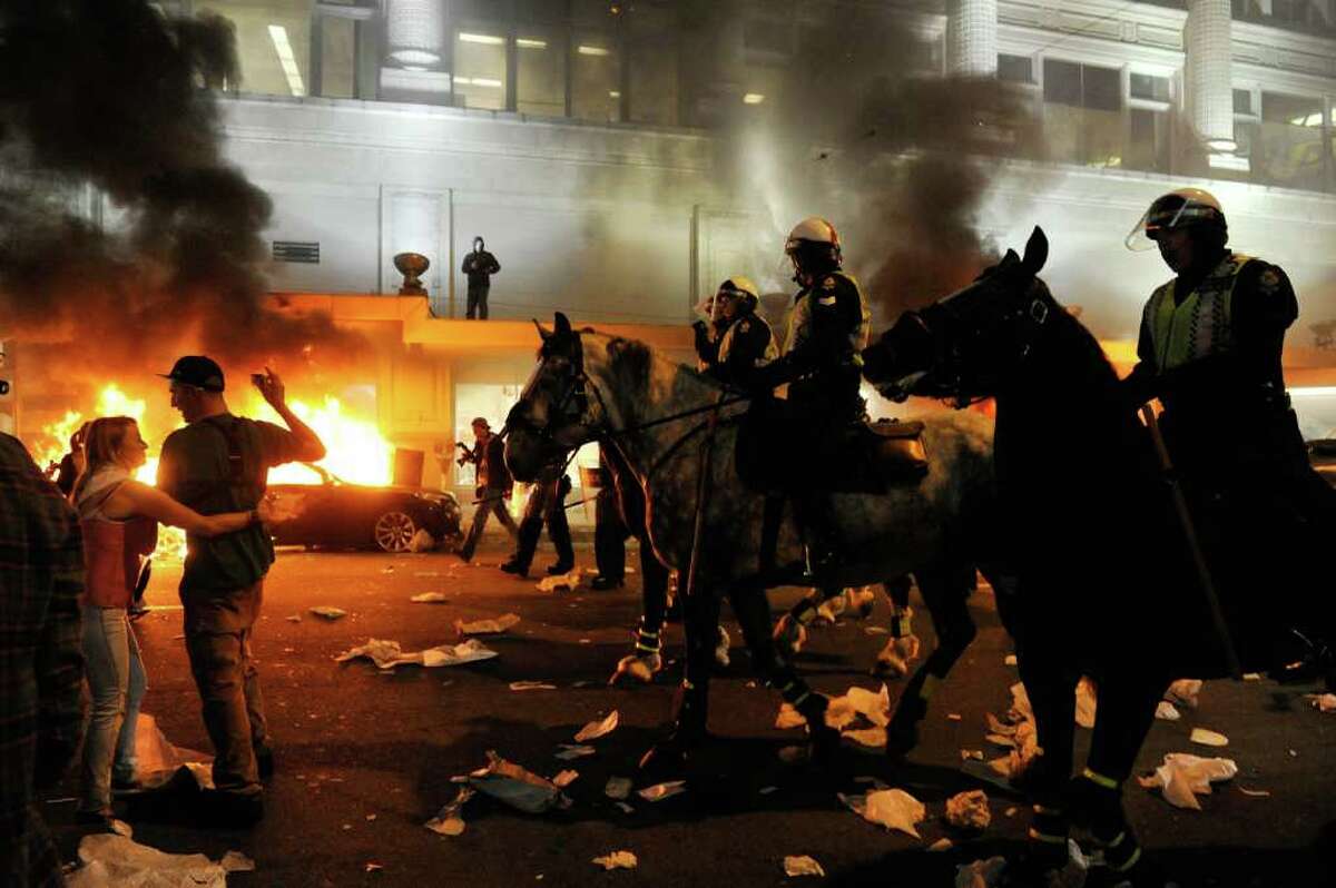 Police on horseback ride through the street past a fire on June 15, 2011 in Vancouver, Canada. Vancouver broke out in riots after their hockey team the Vancouver Canucks lost in Game Seven of the Stanley Cup Finals.