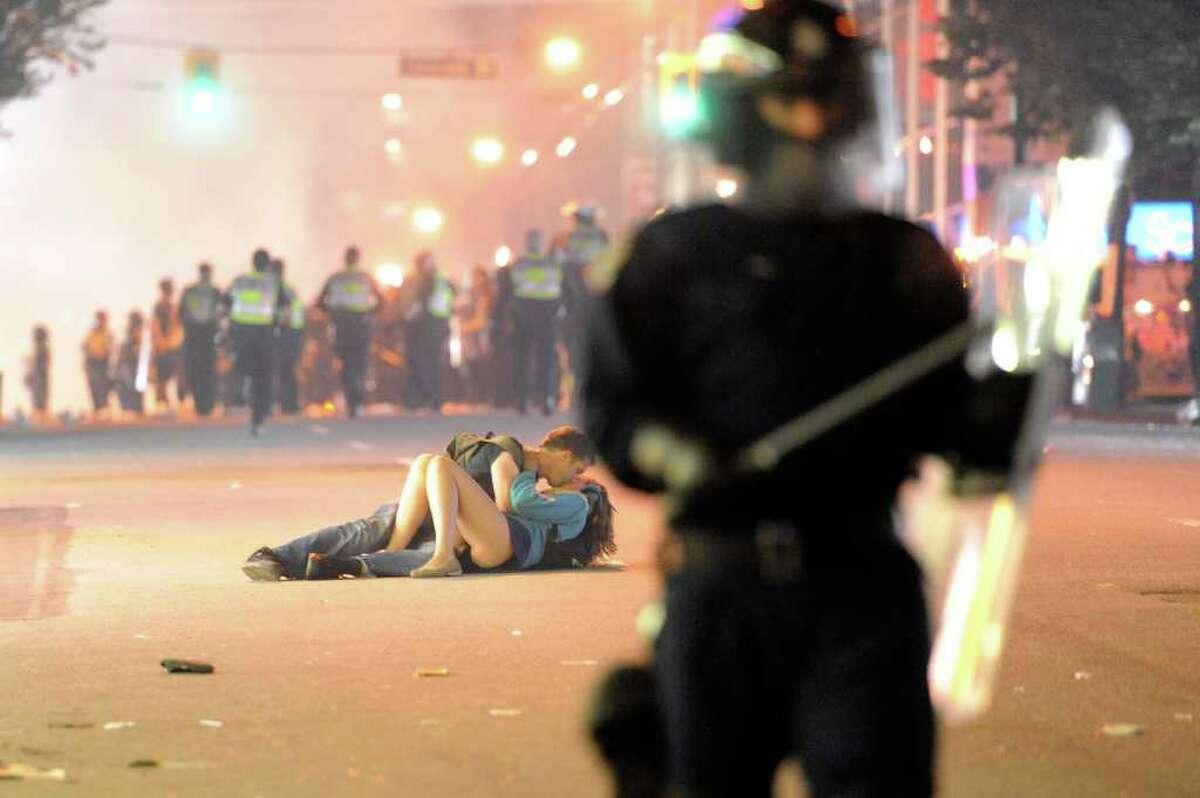 Riot police walk in the street as a couple kiss on June 15, 2011 in Vancouver, Canada. Vancouver broke out in riots after their hockey team the Vancouver Canucks lost in Game Seven of the Stanley Cup Finals.