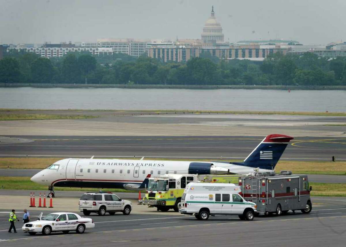 A US Airway plane sits on the tarmac at Reagan National Airport in Washington Sunday, June 19, 2011, surrounded by police and emergency vehicles after a bomb threat was made at an airport ticket counter in Ohio. When the plane landed, authorities swept the plane for explosives and interviewed the 44 passengers aboard. An FBI spokesman says no explosives were found aboard. (AP Photo/Susan Walsh)