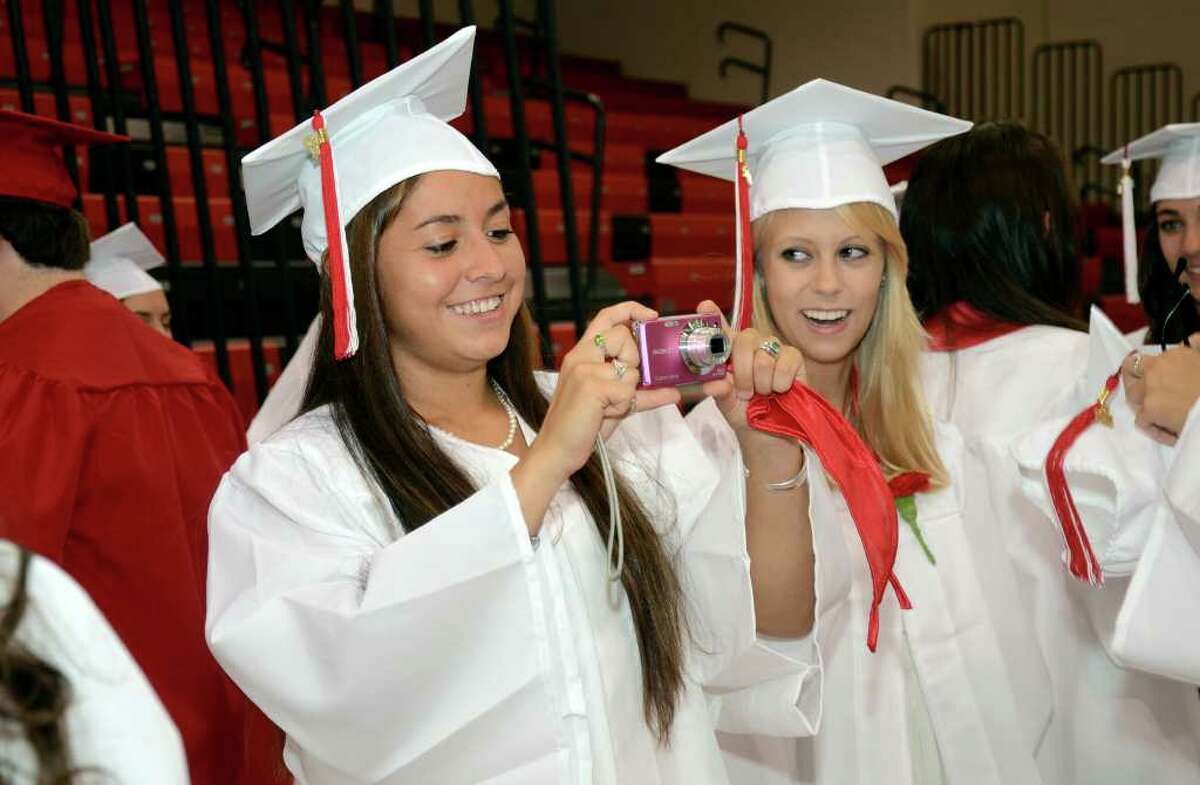 Charlotte Stuifzand, at right, looks on as classmate Lauren Freeland takes a photo to memorialize their last moments as seniors in the New Canaan High School gymnasium during the 2011 New Canaan High School Commencement on Tuesday, June 21, 2011.