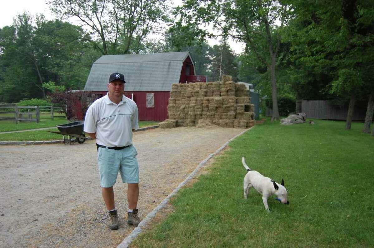 Summer riding camp will go on at Silvermine Farm, owned by Ken Markosky, depicted here with his dog Daytona, whose taken a hoof pick from the barn, during a recent visit. Markosky is running the stable as smoothly as possible despite an indoor riding arena collapsing under the weight of three feet of snow Jan. 27.