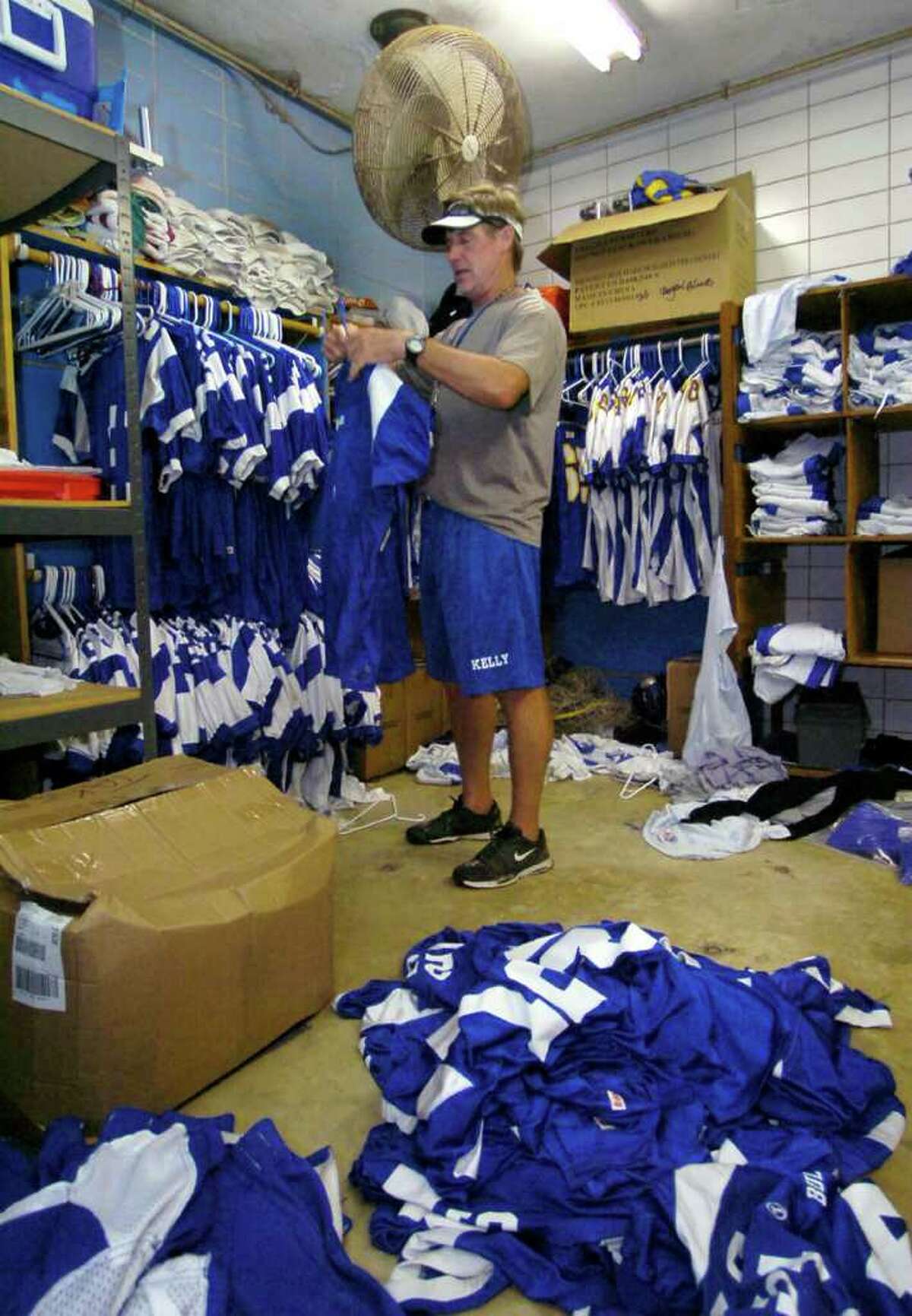 Kelly High School head football coach Mike Long hangs up clean jerseys in the team's equipment room after Friday morning's practice. Dave Ryan/The Enterprise