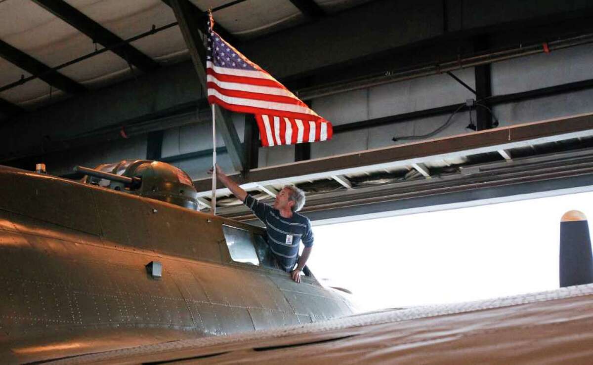 Alan Peover mounts an American flag atop the B-17 on June 30, 2011, before its move from a hangar at Boeing Field, in Seattle, to the Museum of Flight.