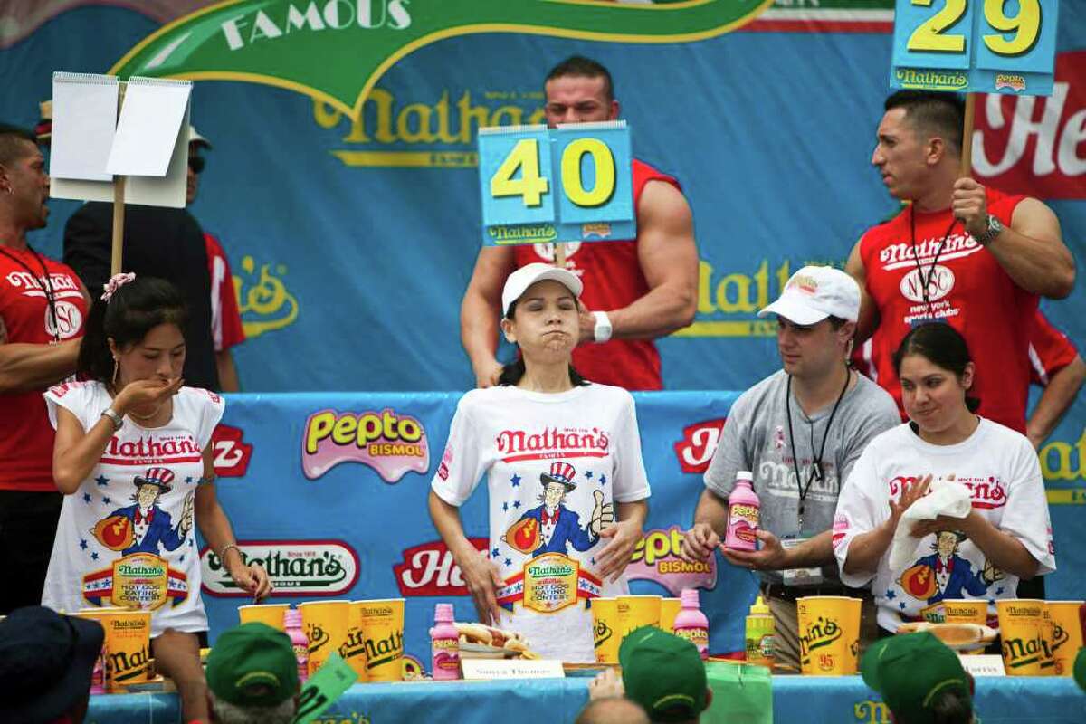 NEW YORK, NY - JULY 4: Sonya Thomas (C) competes in the 2011 Nathan's Famous Fourth of July International Hot Dog Eating Contest at the original Nathan's Famous in Coney Island on July 4, 2011 in the Brooklyn borough of New York City. Thomas also known as 'The Black Widow' won this year's first ever women's competition by eating 40 hot dogs. (Photo by Ramin Talaie/Getty Images)