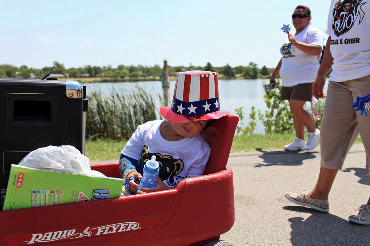 Vini Acosta-Torres, 3, sleeps in a wagon also holding the speaker for the music for the BearsNation cheerleaders during the "Salute to the Red, White and Blue Parade" at Woodlawn Lake Park on July 4, 2011.