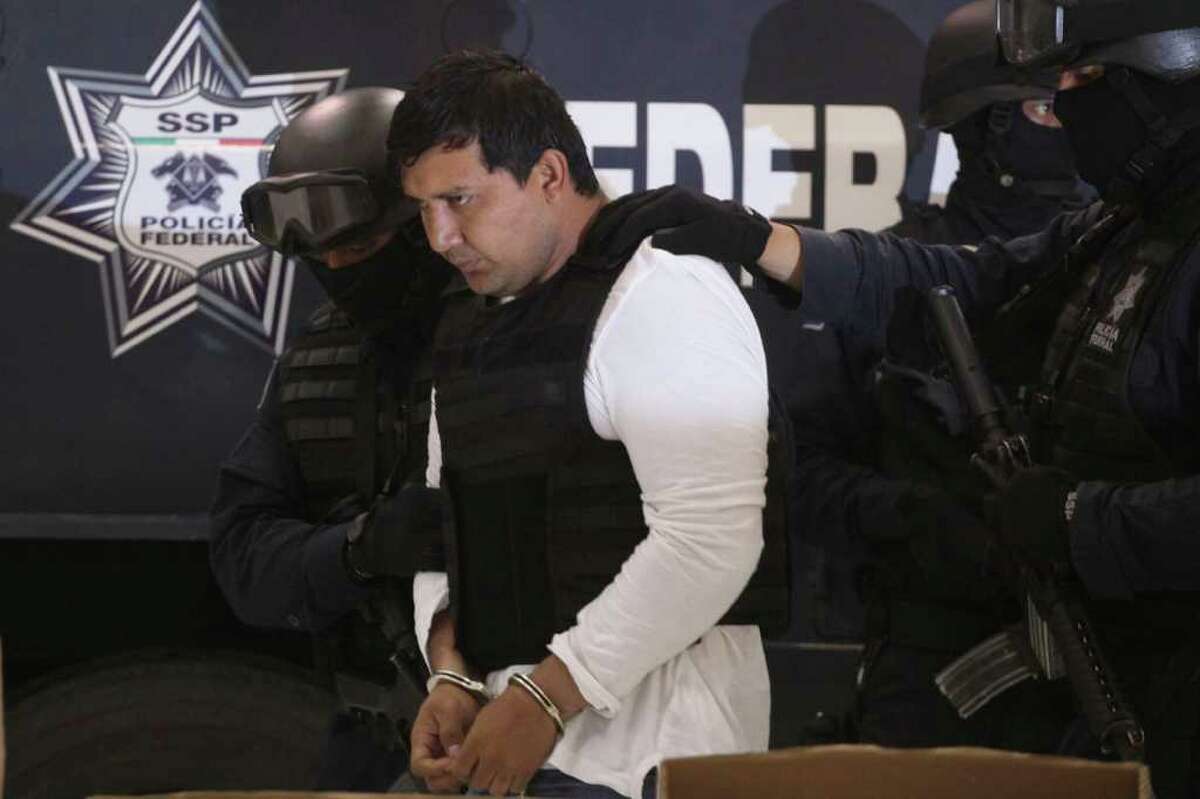 Federal Police agents escort Jesus Enrique Aguilar, alias "El Mamito", to his presentation to the media in Mexico City, Monday July 4, 2011. Police believe Aguilar is connected with the killing of a U.S. Immigration and Customs Enforcement agent. According to authorities Aguilar is a former member of the Mexican Army and allegedly a co-founder of the Zetas drug cartel. (AP Photo/Alexandre Meneghini)