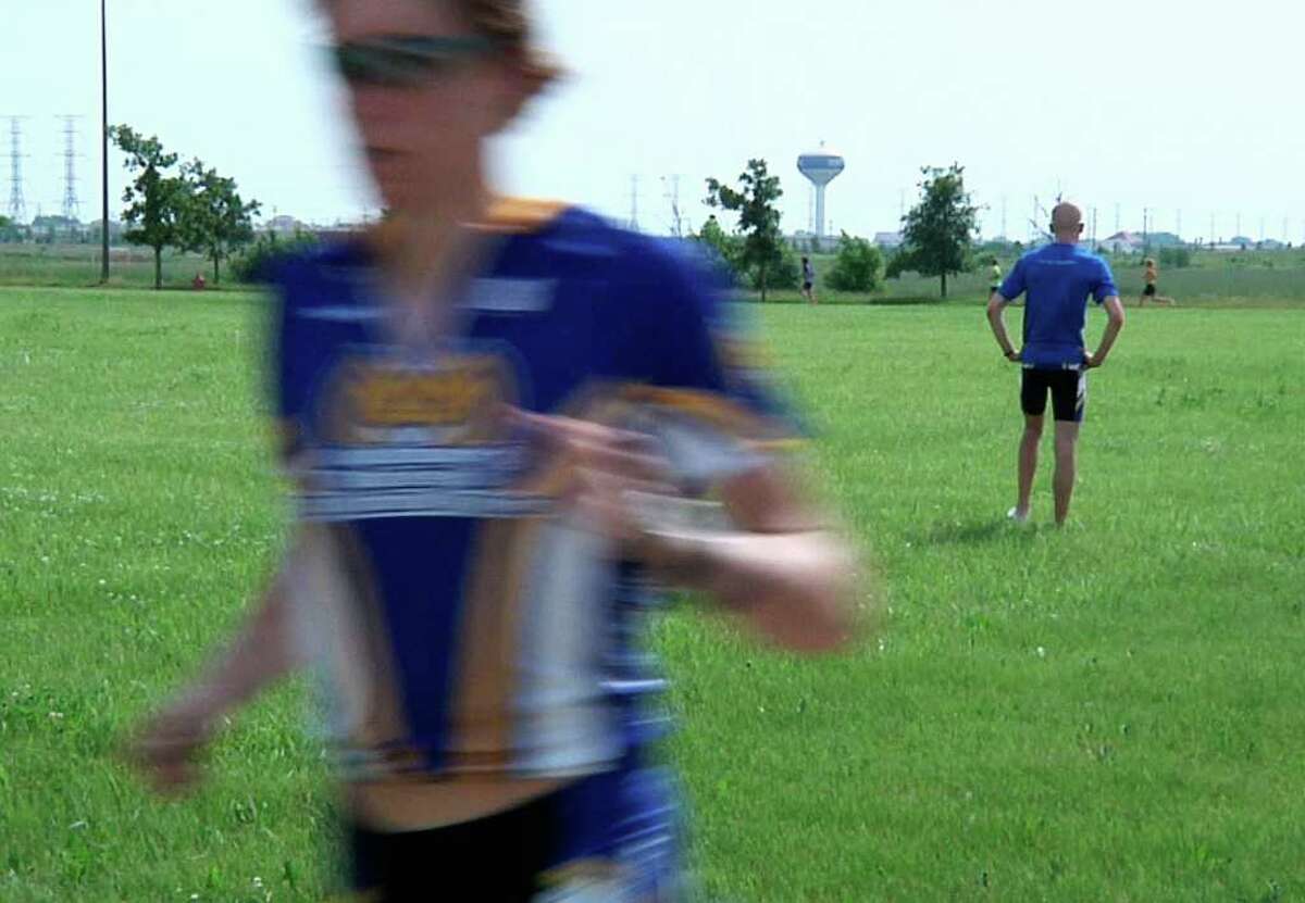 In a photo from AP video taken June 21, 2011, Kevin McDowell rests in the background after biking, as teammate Lukas Verzbicas runs past in Aurora, Ill. McDowell, who was diagnosed with Hodgkin's lymphoma this spring, is still able to train with his teammates sometimes, though sometimes has to rest while they continue on. McDowell, an elite triathlete, had been a favorite to win the triathlon event at the Junior World Championships this September in China until he was diagnosed with Hodgkin's lymphoma this spring. Verzbicas, who has committed to a running career at the University of Oregon, made the decision to compete in McDowell's place to honor his friend. (AP Photo/Martha Irvine)