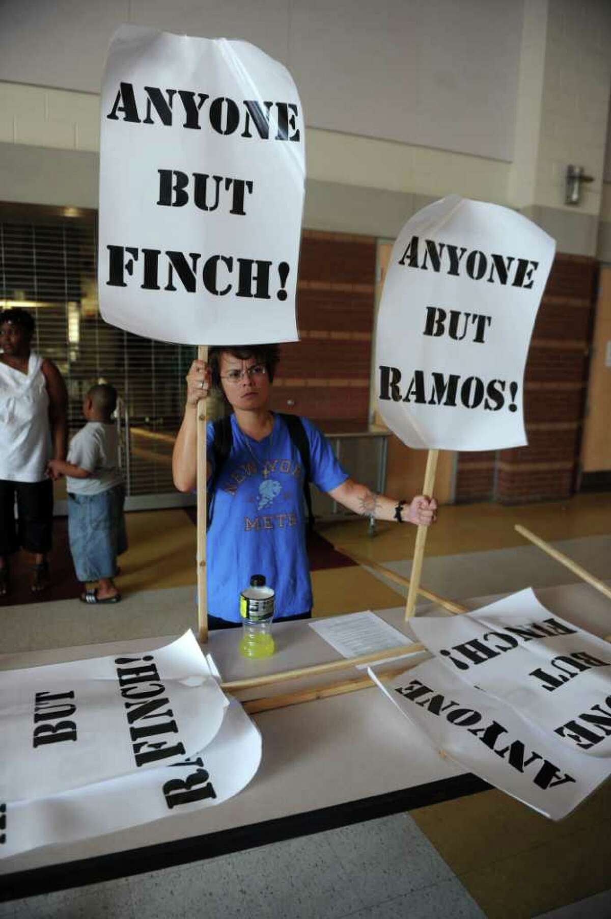 Cat Vendryes-Martin hold up signs protesting the Mayor Bill Finch and Superintendant of School Dr. John Ramos during a special meeting of the Bridgeport Board of Education was held at Cesar A. Batalla Elementary School in Bridgeport, Conn. on Tuesday July 5, 2011.