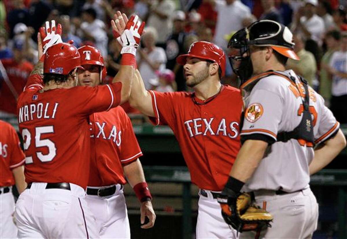 Texas Rangers' Mike Napoli, left, is congratulated by teammates Michael Young, left rear, and Mitch Moreland, right rear, following his three-run home run that scored the duo, as Baltimore Orioles catcher Matt Wieters stands by during the seventh inning of a baseball game, Wednesday, July 6, 2011, in Arlington, Texas. The Rangers won 13-5. (AP Photo/Tony Gutierrez)