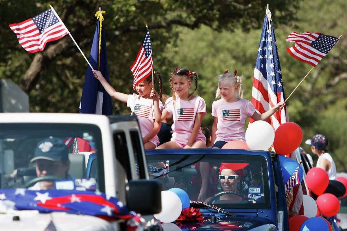 Samantha Daniel (from left), Alyssa Stewart and Katie Stewart wave American flags from atop their jeep during the Hollywood Park 4th of July Parade on July 4, 2011. Photo by Marvin Pfeiffer