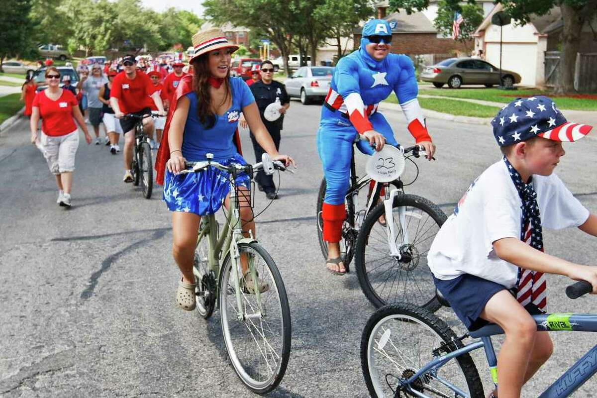Captain America (Danny Silva) and Wonder Woman (Laura Silva) ride their bikes with the rest of the crowd as the Woodridge Indepence Day celebration makes it way up Woodrige Bluff on July 2, 2011. Photo by Marvin Pfeiffer