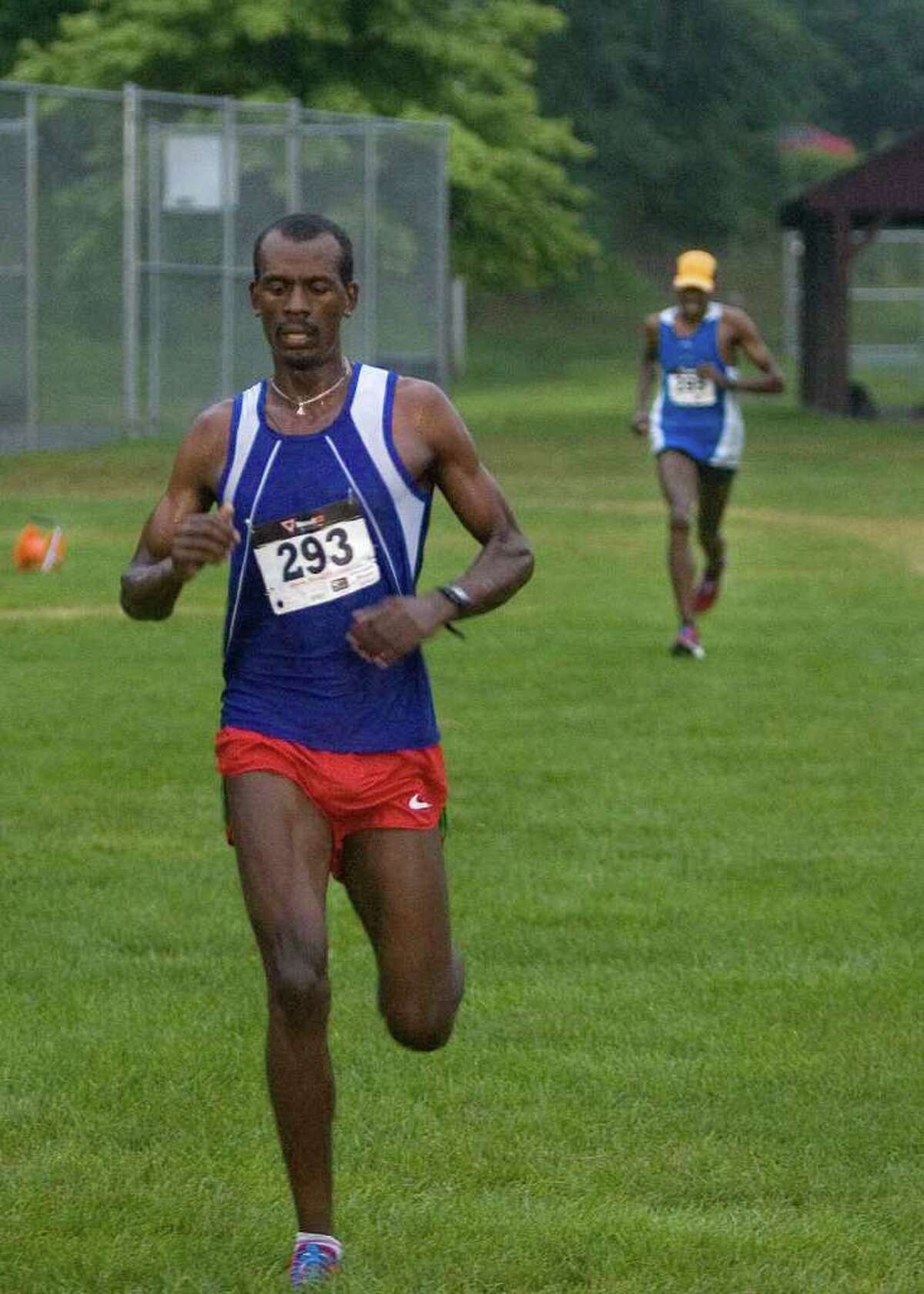 Kumsa Megersa, left, crosses the finish line in first place as fellow Bronx, NY, resident Abiyot Endale finishes in second place during the New Milford Moonlight Run 5K road race on Friday, July 8, 2011. Both men are originally from Ethiopia.