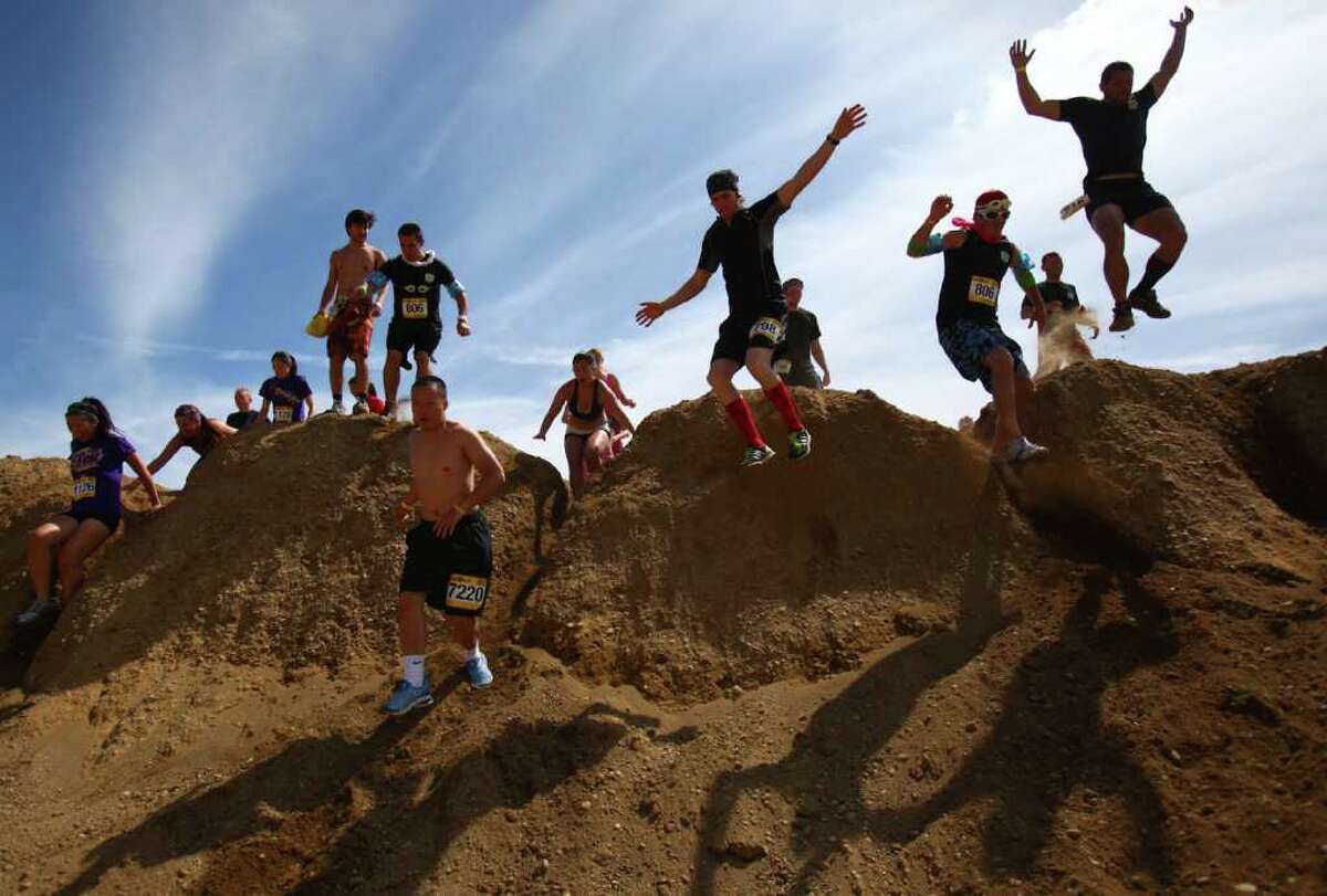 Some of the thousands of runner leap from a dirt hill during the Dirty Dash Seattle 10k mud run on Saturday, July 9, 2011 at PGP Motorsports Park in Kent. Nearly 4,000 people participated in the inaugural event in the Seattle area.