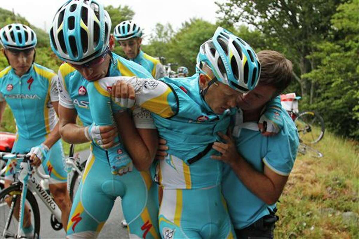 Alexande Vinokourov of Kazakhstan, second right, is helped by his teammates after crashing during the 9th stage of the Tour de France cycling race over 208 kilometers (129 miles) starting in Issoire and finishing in Saint Flour, central France, Sunday July 10, 2011. (AP Photo/Christophe Ena)