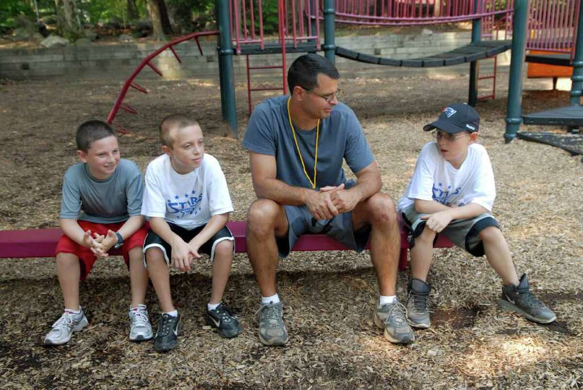 Matt Shoztic, a 5th grade teacher at Westover School, takes a break with Sam Diamond, Nicholas Teitler and Harry Mascolo at summer sports camp at Northeast School in Stamford, Conn. on Monday July 11, 2011.