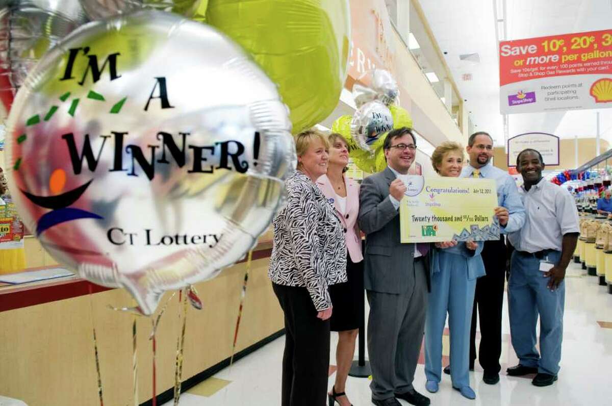 (center) Frank Farricker, chairman of the board of CT Lottery, presents Arlene Putterman, manager of community affairs for Stop & Shop, with a check for $20,000 as a bonus for selling the winning Lucky-4-Life lottery ticket in Stamford, Conn. on Tuesday July 12, 2011. They are joined by other employees of CT Lottery and Stop & Shop.