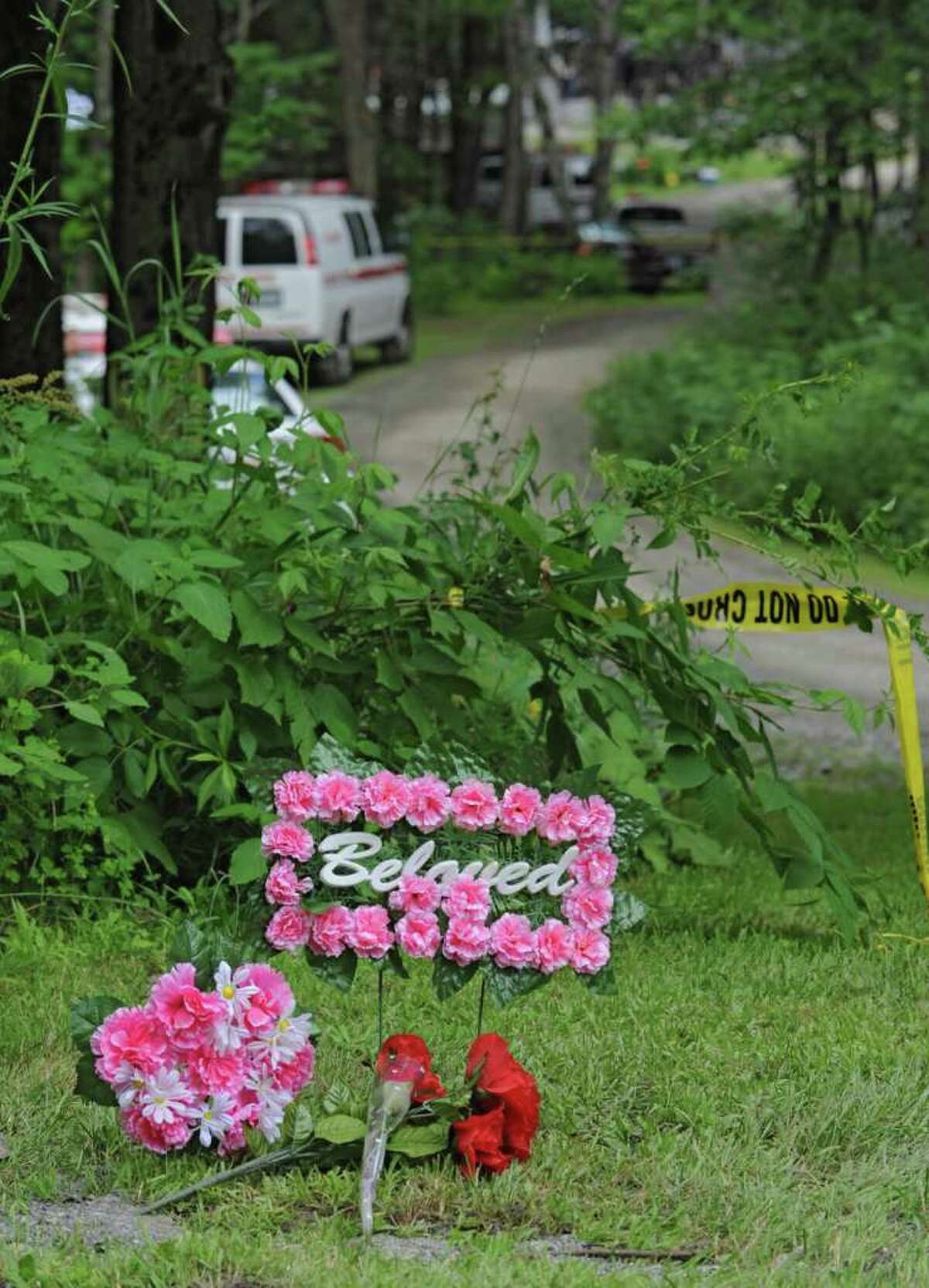 Flowers are left at the end of a driveway on property where authorities said three people were shot to death by Matthew Slocum, who then set the house on fire Wednesday in White Creek. (Lori Van Buren / Times Union)