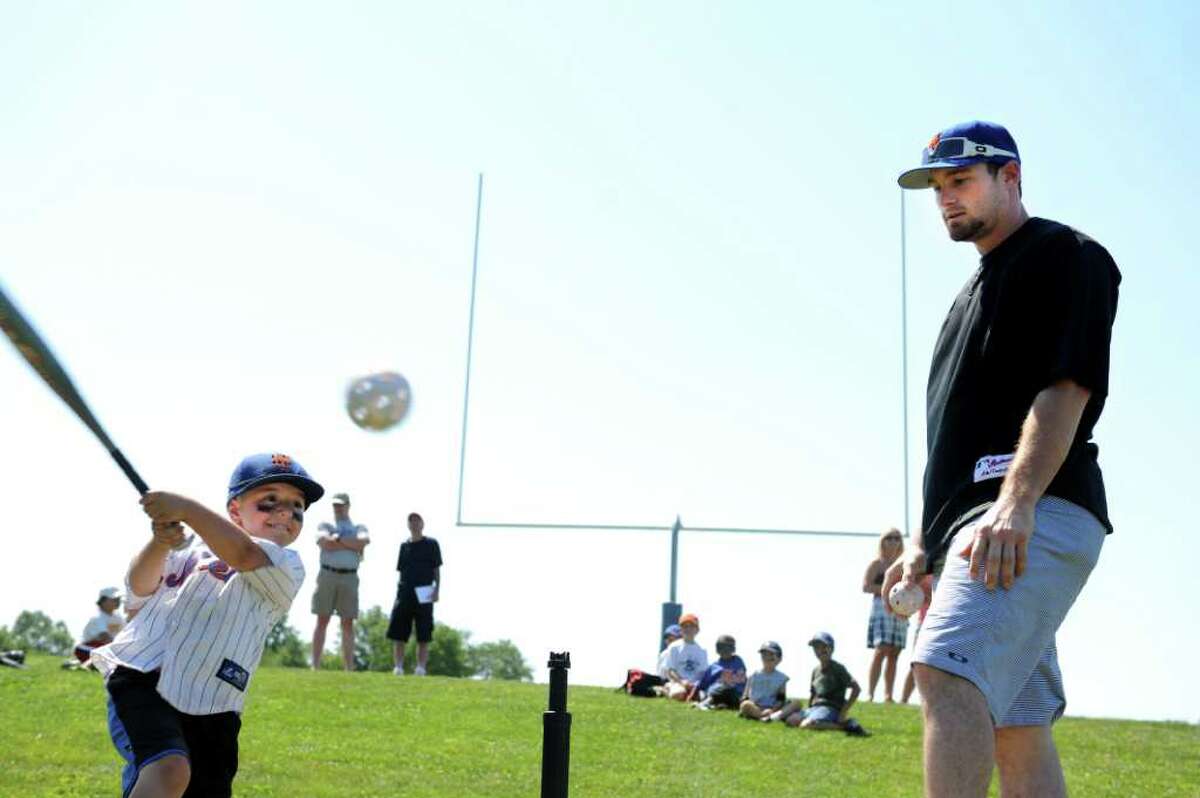 New York Mets player Daniel Murphy helps five-year-old Trevor Diaco, of Westport, with his swing Friday, July 15, 2011 during a visit to Baseball World Training School in Westport, Conn.