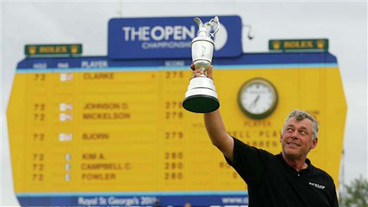 Northern Ireland's Darren Clarke holds up the Claret Jug trophy in front of the scoreboard on the 18th green as he celebrates winning the British Open Golf Championship at Royal St George's golf course Sandwich, England, Sunday, July 17, 2011. (AP Photo/Peter Morrison)