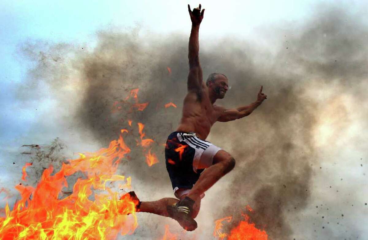 A participant leaps over fire during the inaugural Warrior Dash Washington on Sunday, July 17, 2011 in North Bend. Approximately 23,000 people competed in the 3.55 mile course which included a mud pit and flaming obstacles.