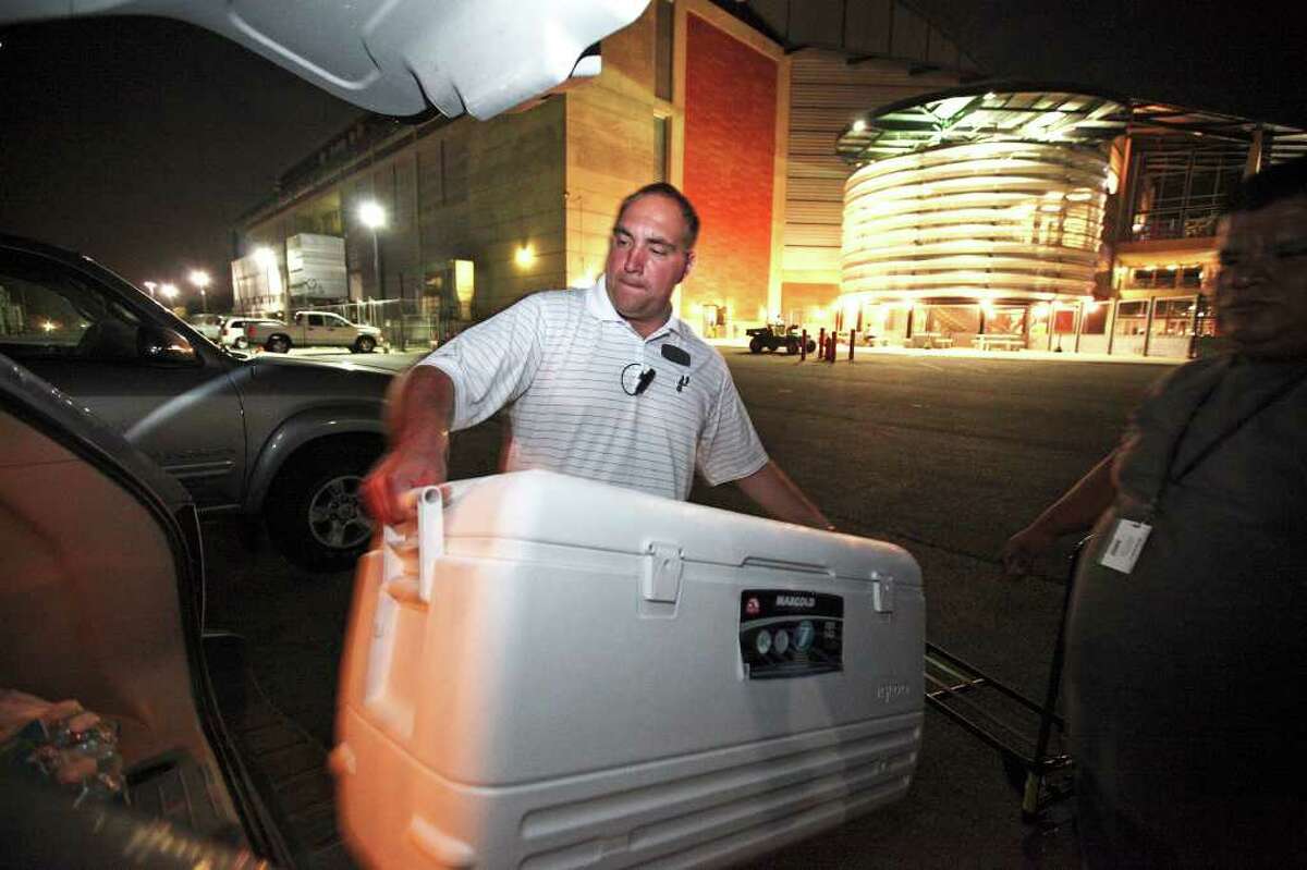ARAMARK General Manager Tim Witkowski loads a cooler of unsold hot dogs and pretzels into Michael Martinez’s car at the AT&T Center so the food can be donated to Haven for Hope.