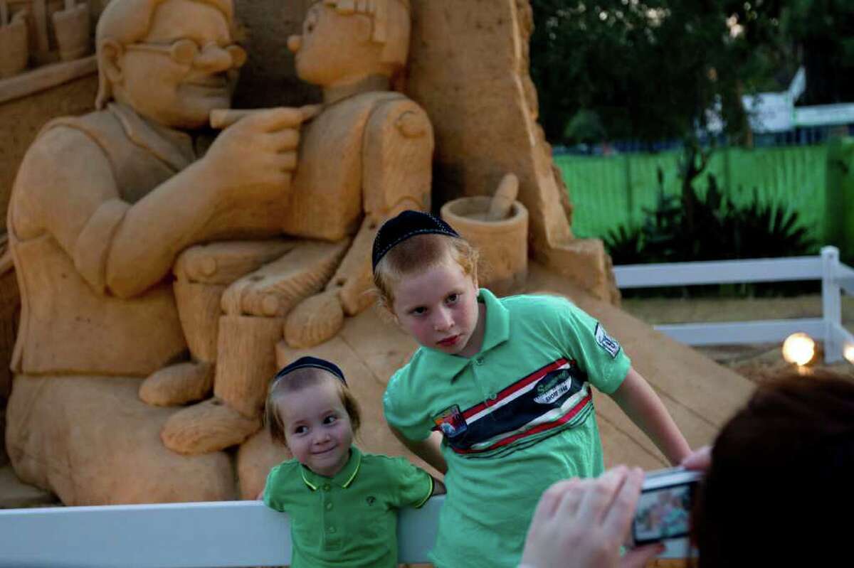Two Orthodox Jewish brothers pose for a photograph for their mother in front of "Gepetto and Pinocchio" as they visit the Tales in Sand Exhibition in the Eretz Israel Museum in Tel Aviv, on July 20, 2011.