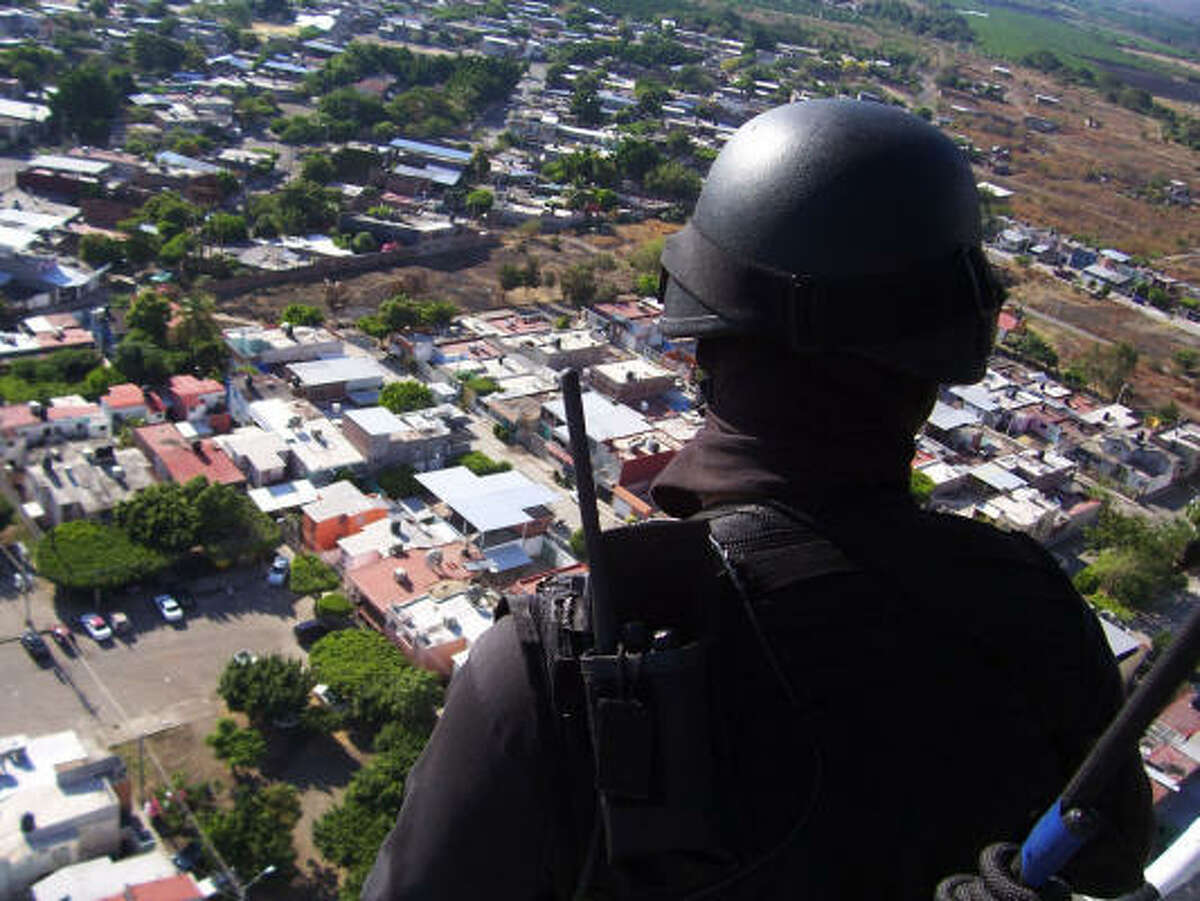 An anti-narcotics agent guards against drug traffickers on a hillside overlooking Uruapan, Michoacán, in August following a spate of violence in Michoacán's second-largest city.