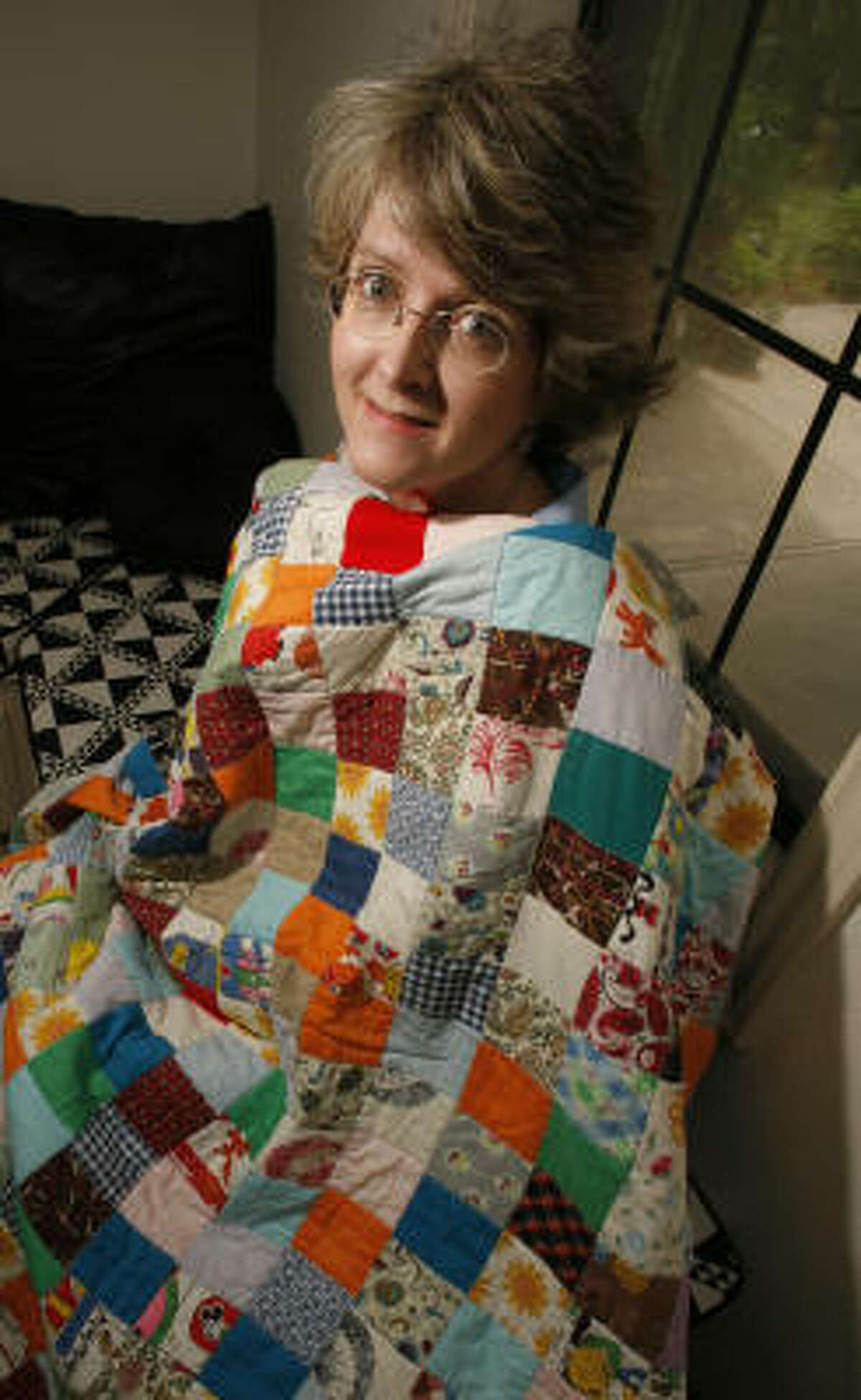 Cynthia England, blanketed by the first quilt she made, has won the top prize at the International Quilt Festival in Houston twice.