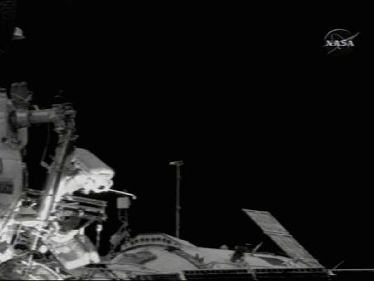 In a frame capture from NASA TV, spacewalker Mikhail Tyurin holds a gold six iron as he stands on the PIRS docking compartment's "cosmic tee box" and prepares to hit a golf ball.