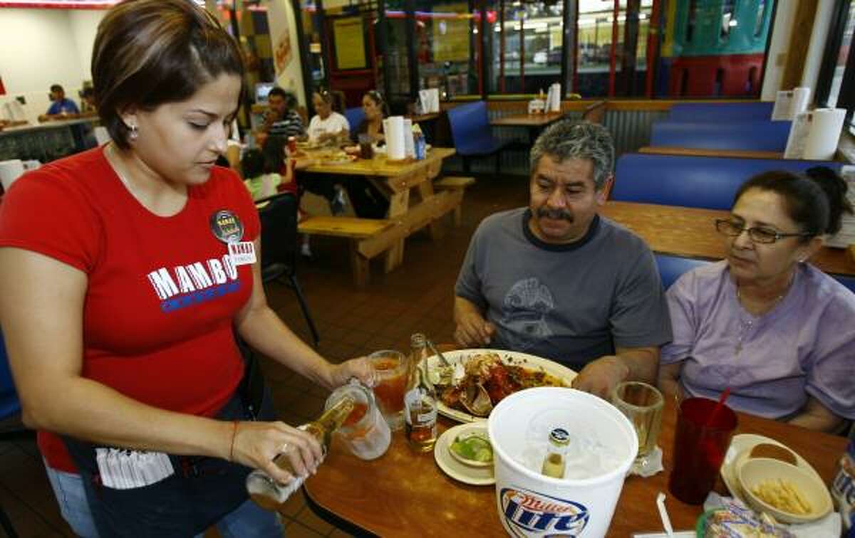 Romelia Lopez, a waitress at Mambo Seafood, pours a michelada for Hector Marquez and his wife Maria Esquivel. 