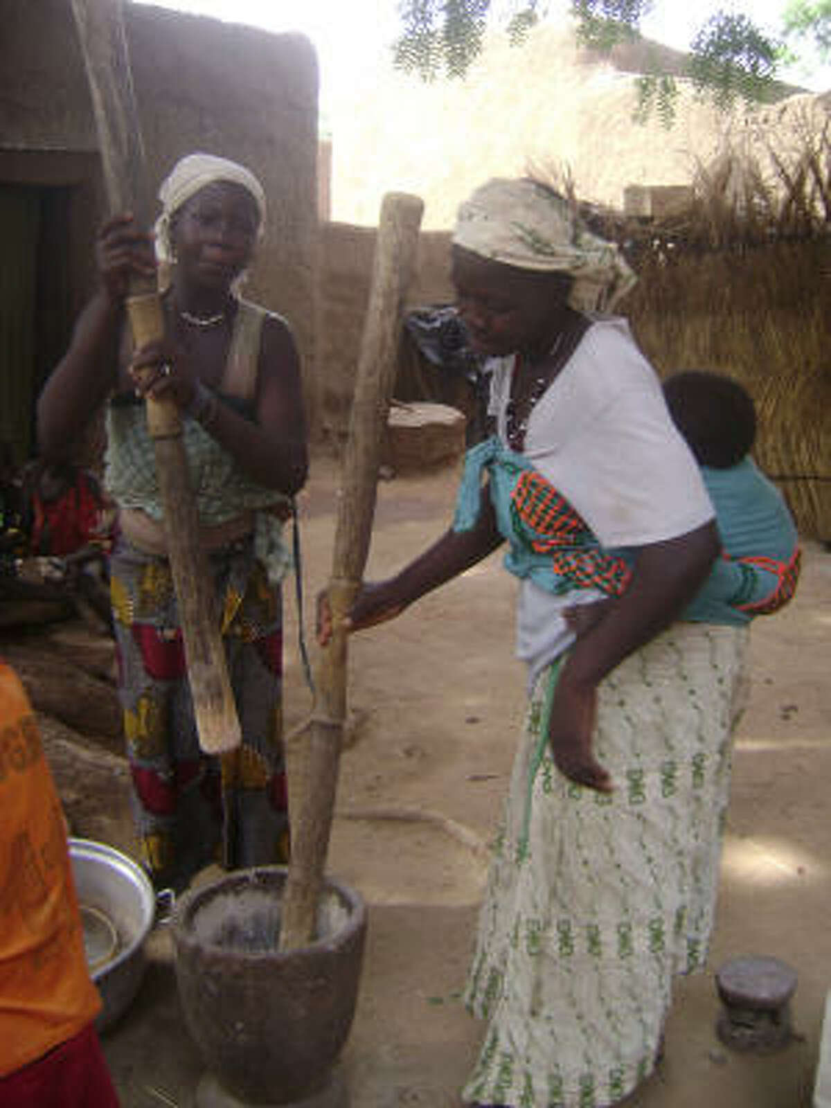 Women in Endé, a Dogon village in central Mali, pound millet to create their evening meal.