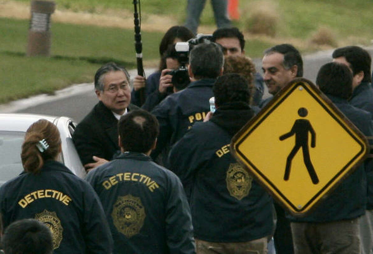 Chilean police officers surround Peru's former President Alberto Fujimori, left, as he leaves his house in Santiago, Chile, to be extradited to Peru.